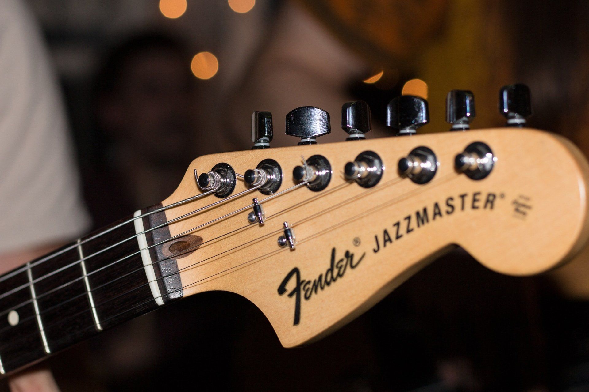 Fender Jazzmaster guitar headstock with tuning pegs, strings, and logo.