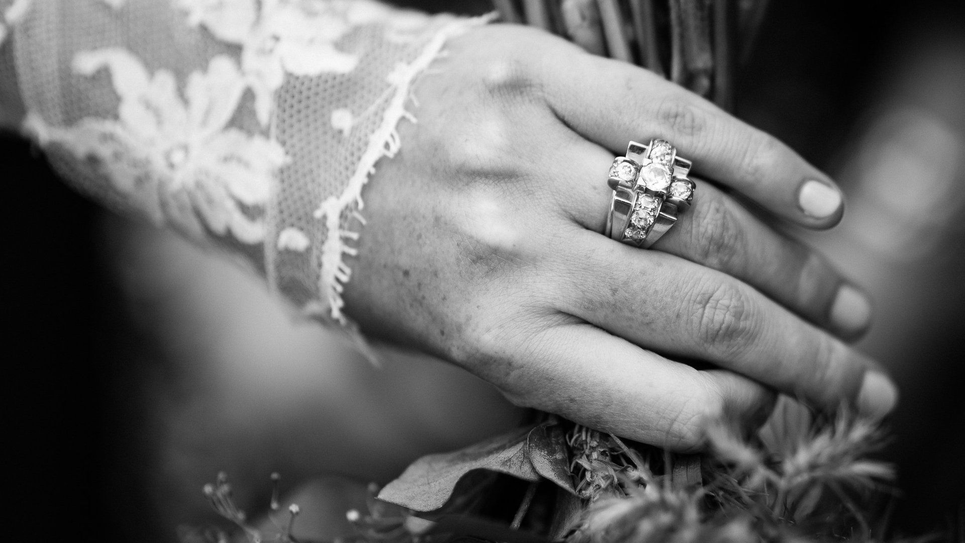 A black and white photo of a bride 's hand with a wedding ring on it.