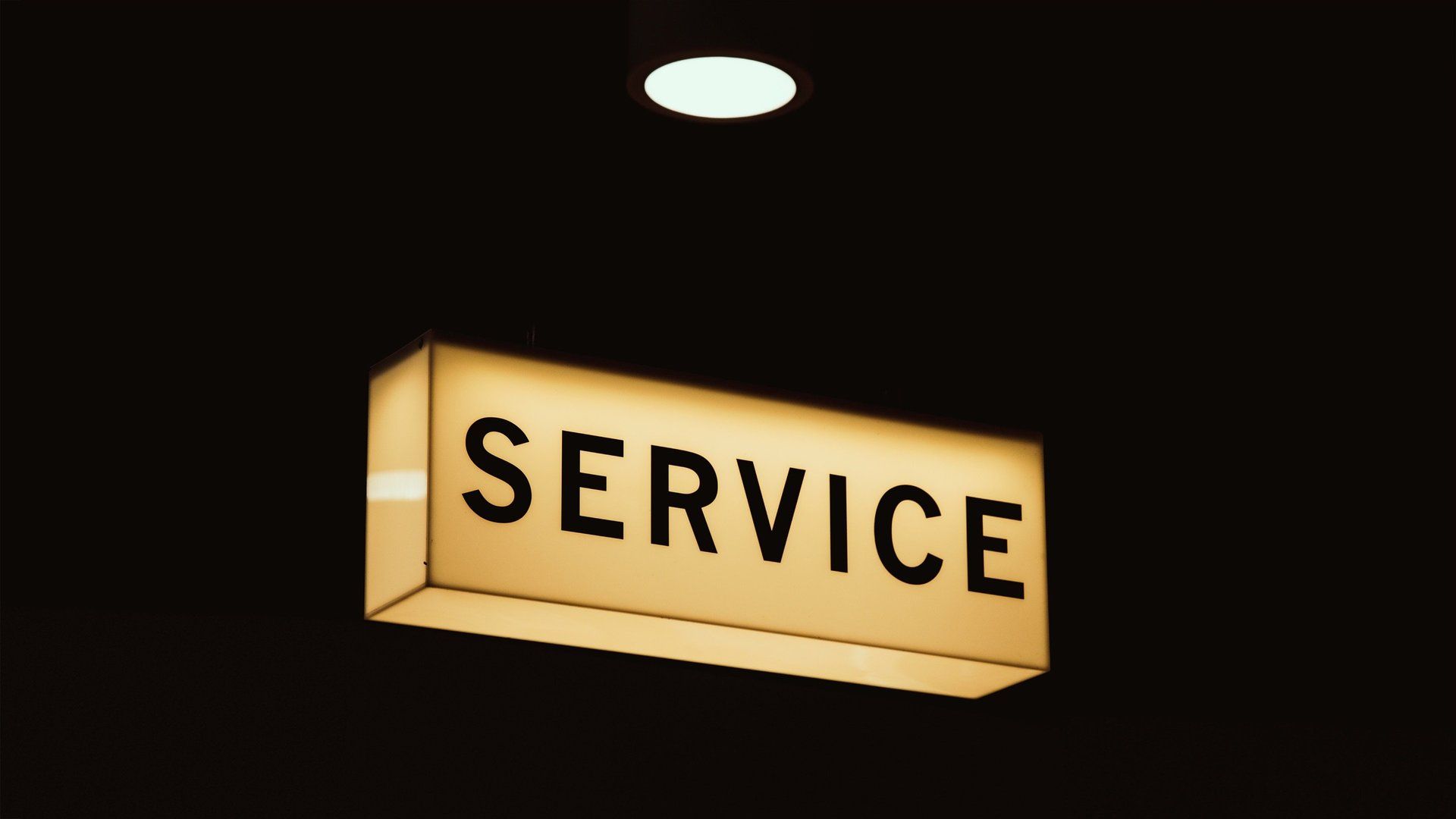 A lighted sign that says service is hanging from the ceiling.