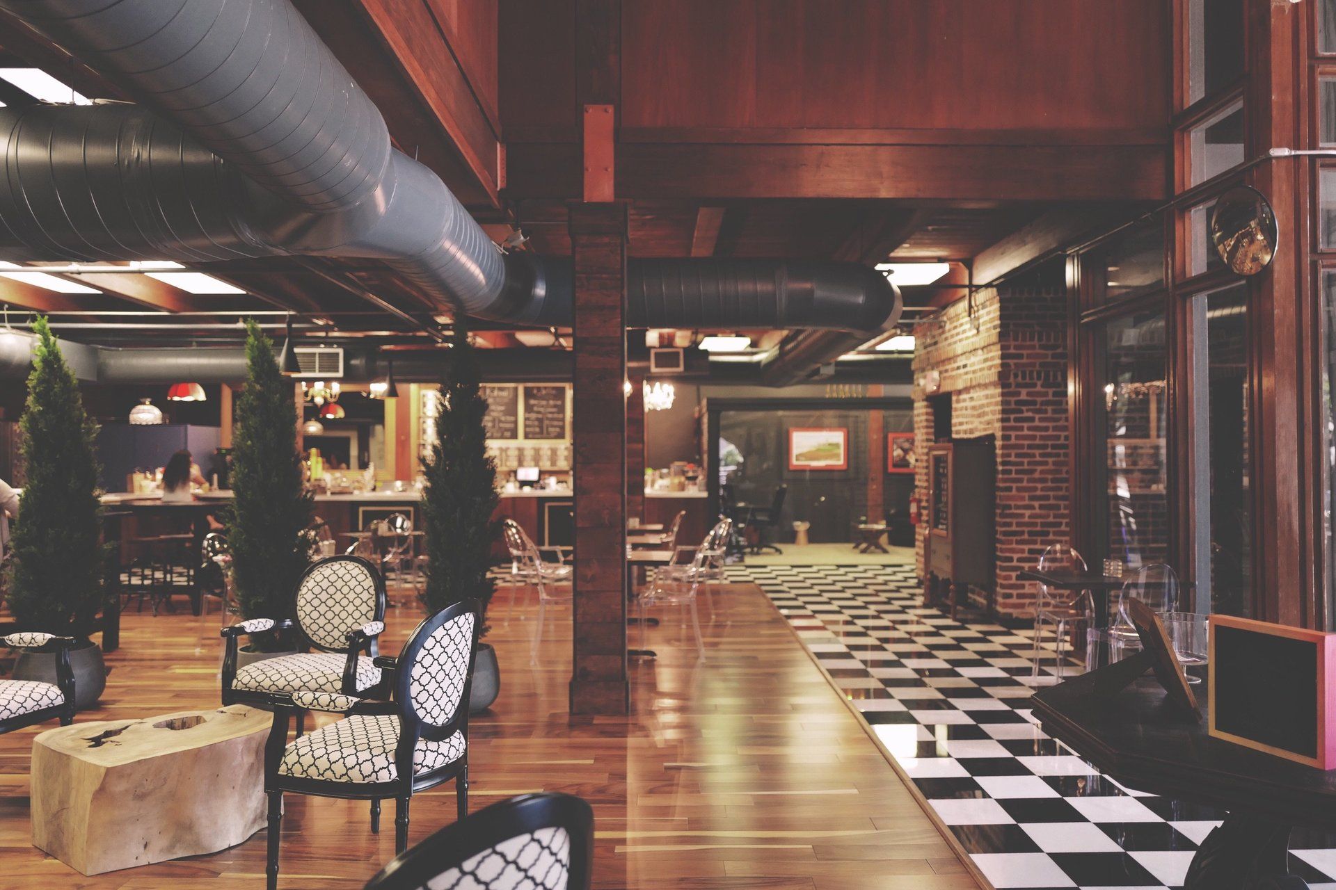 Elegant restaurant interior with patterned chairs, wood floors, and checkered tile.