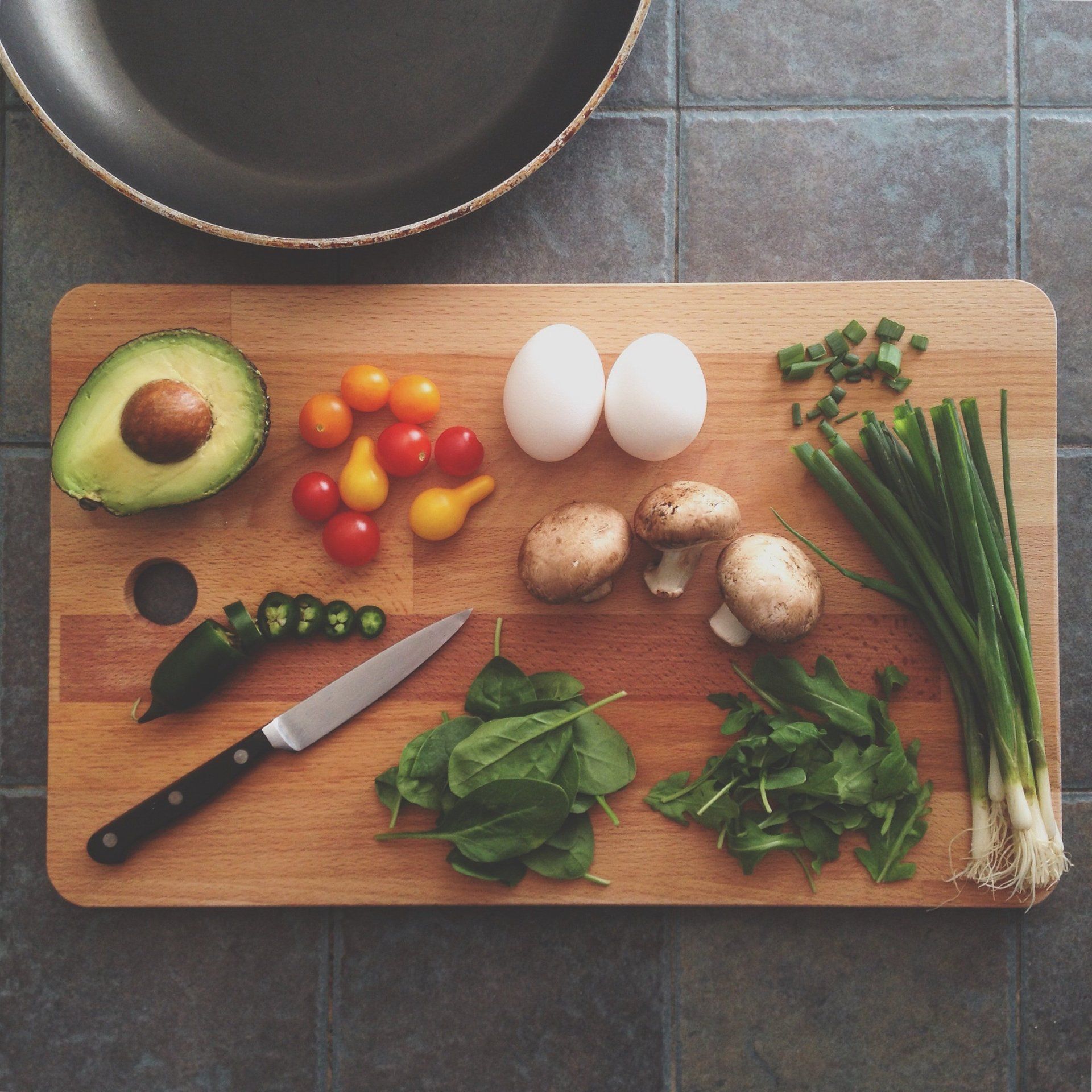 A wooden cutting board with vegetables and eggs on it