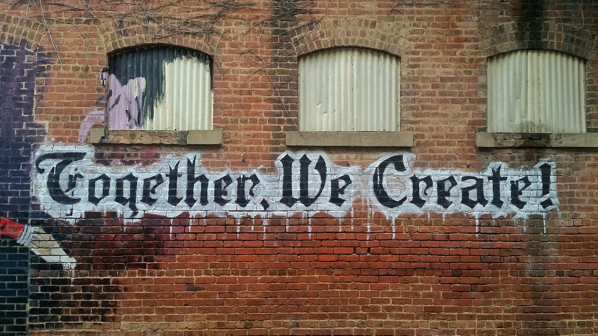 a brick wall with graffiti on it that says together we create