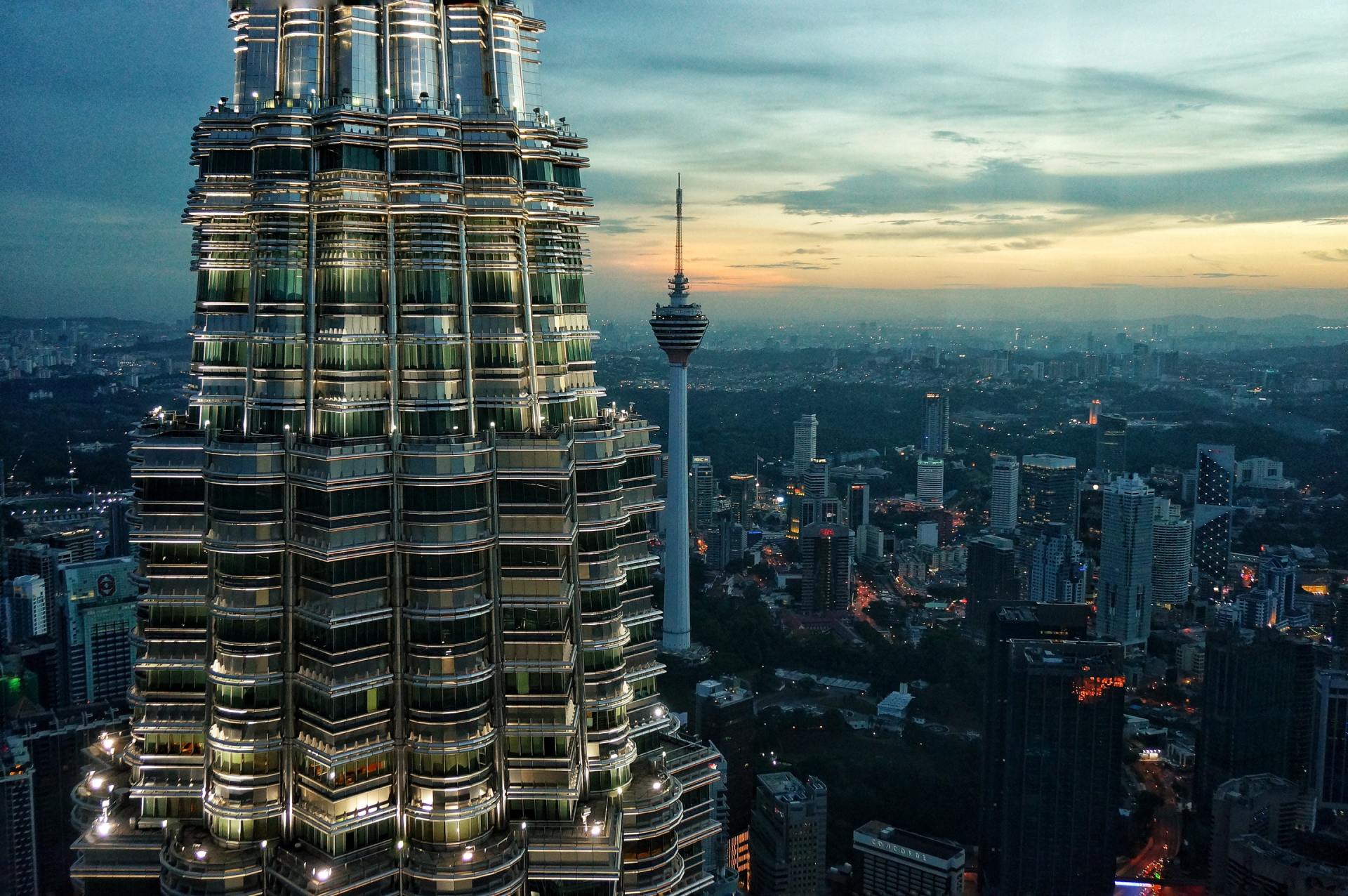 An aerial view of a city with a tall building in the foreground and a tower in the background.