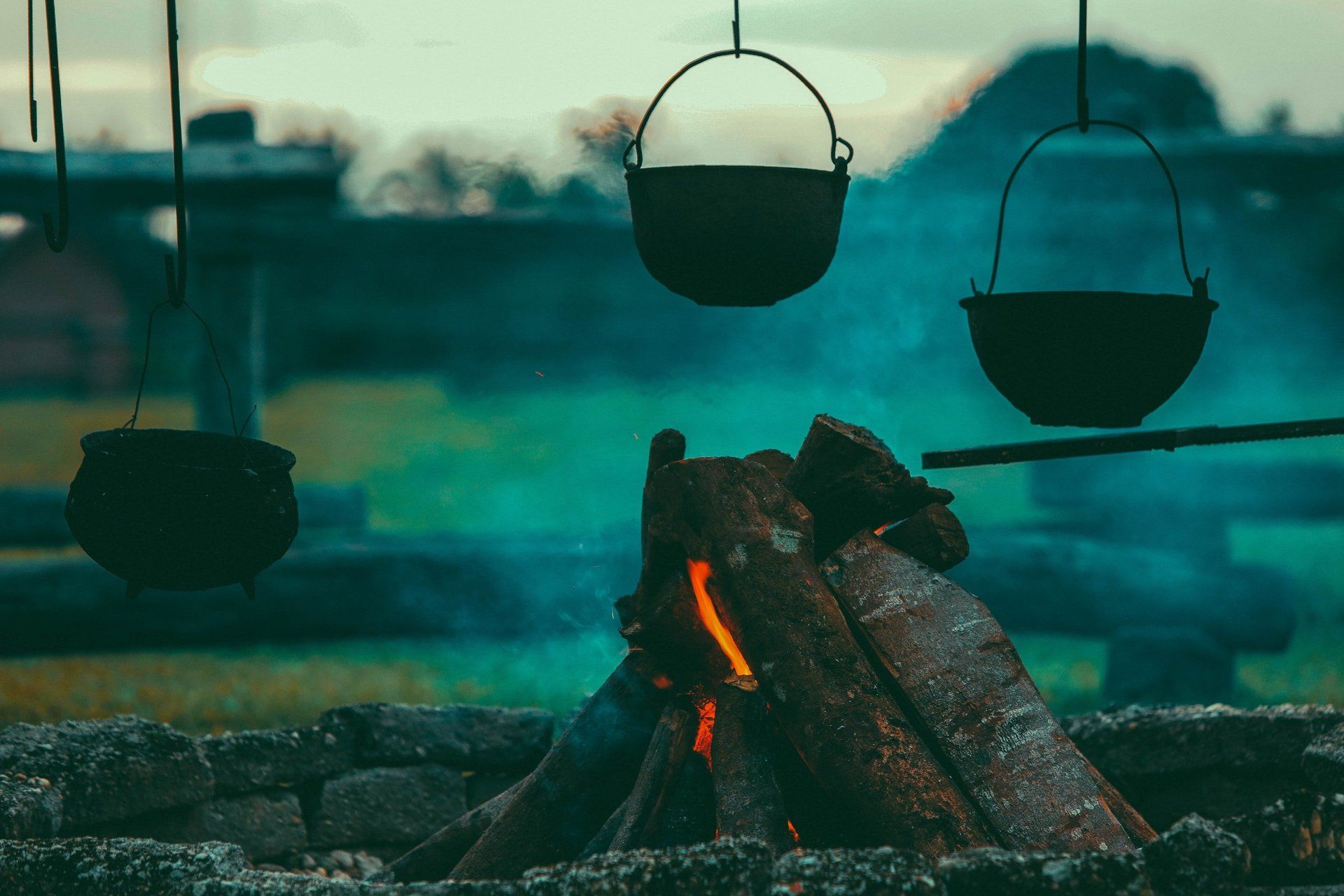 A group of pots hanging over a fire.