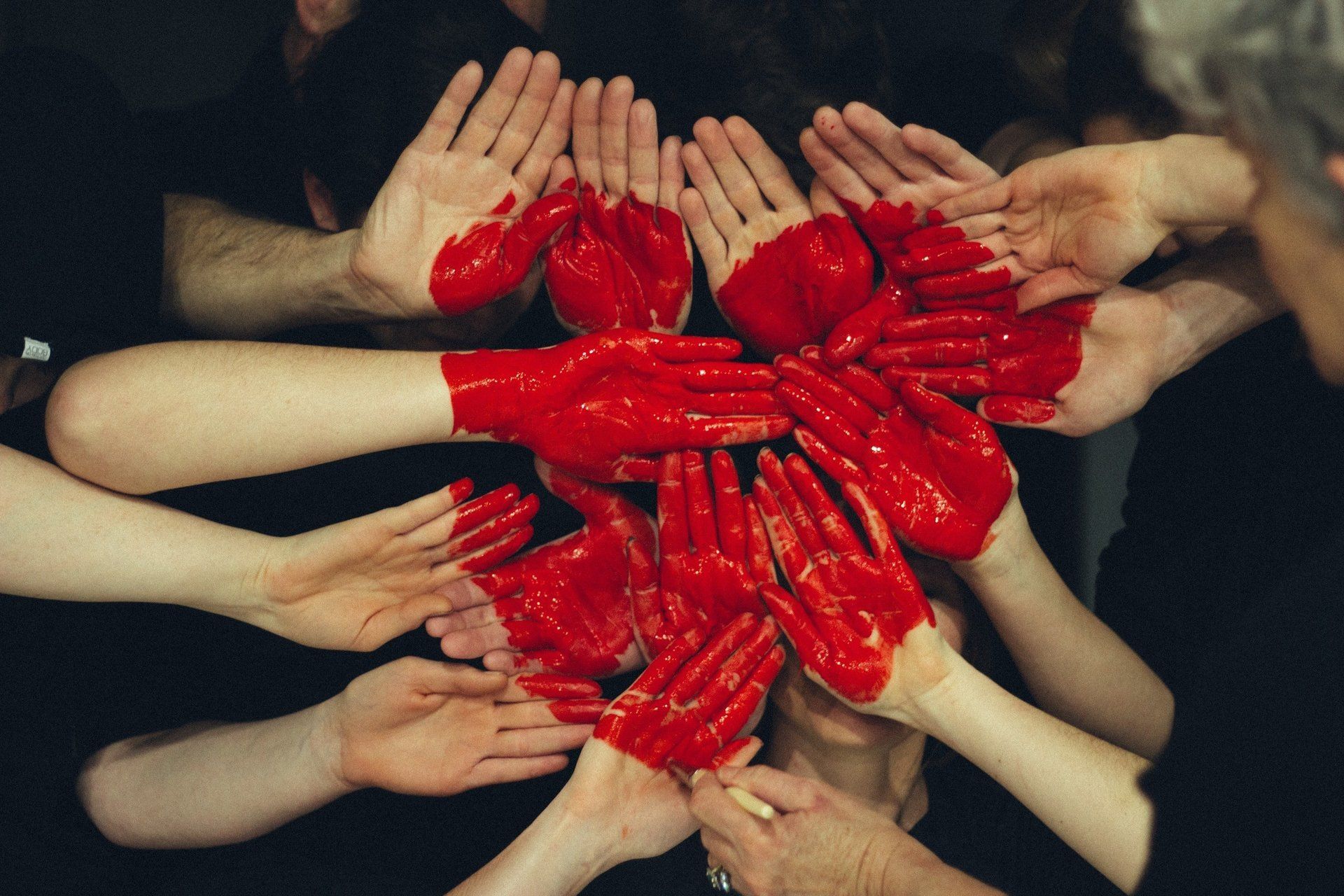A group of people are making a heart with their hands painted red