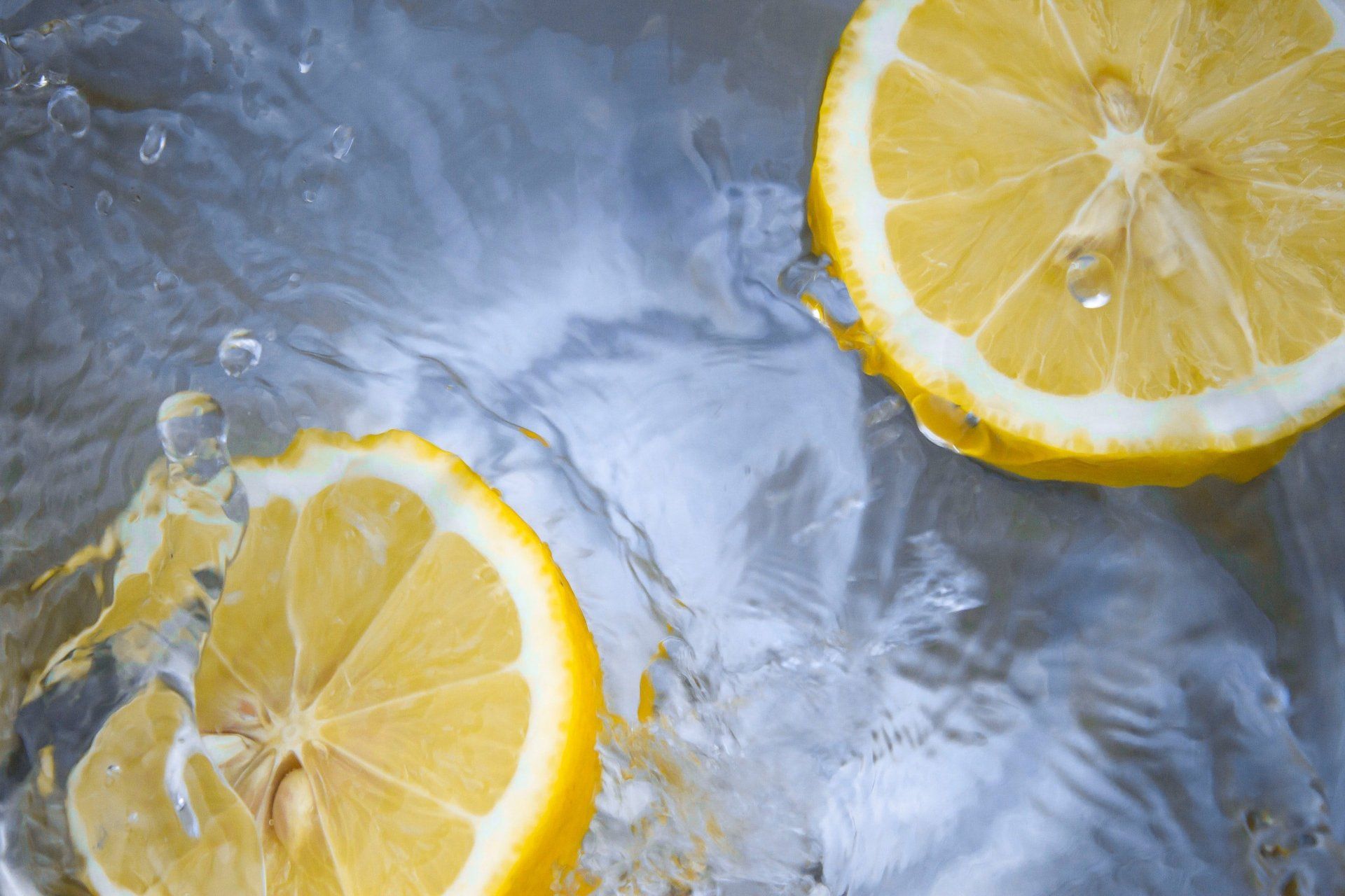 Two slices of lemon are splashing into a glass of water.