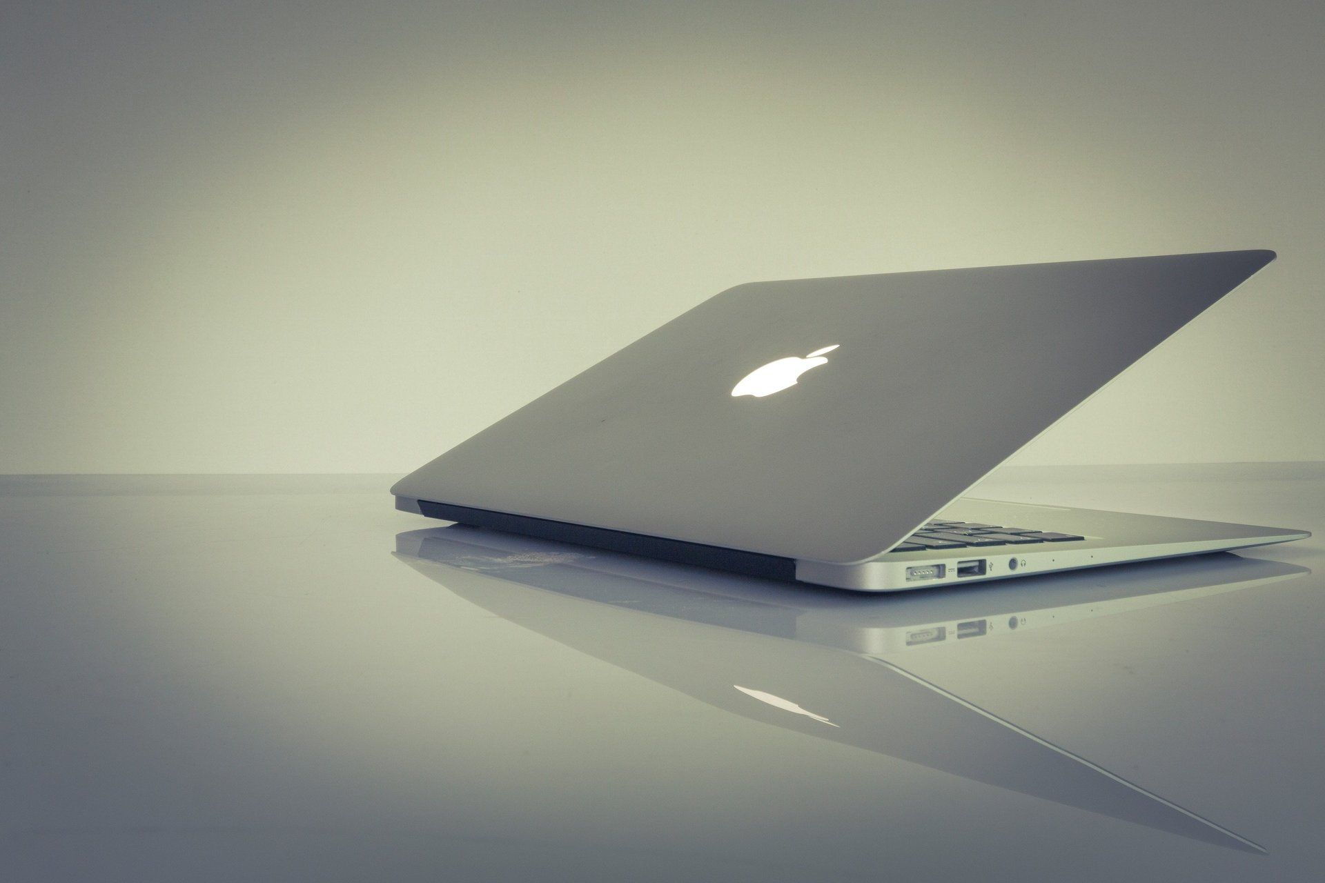 An apple laptop is open and sitting on a table
