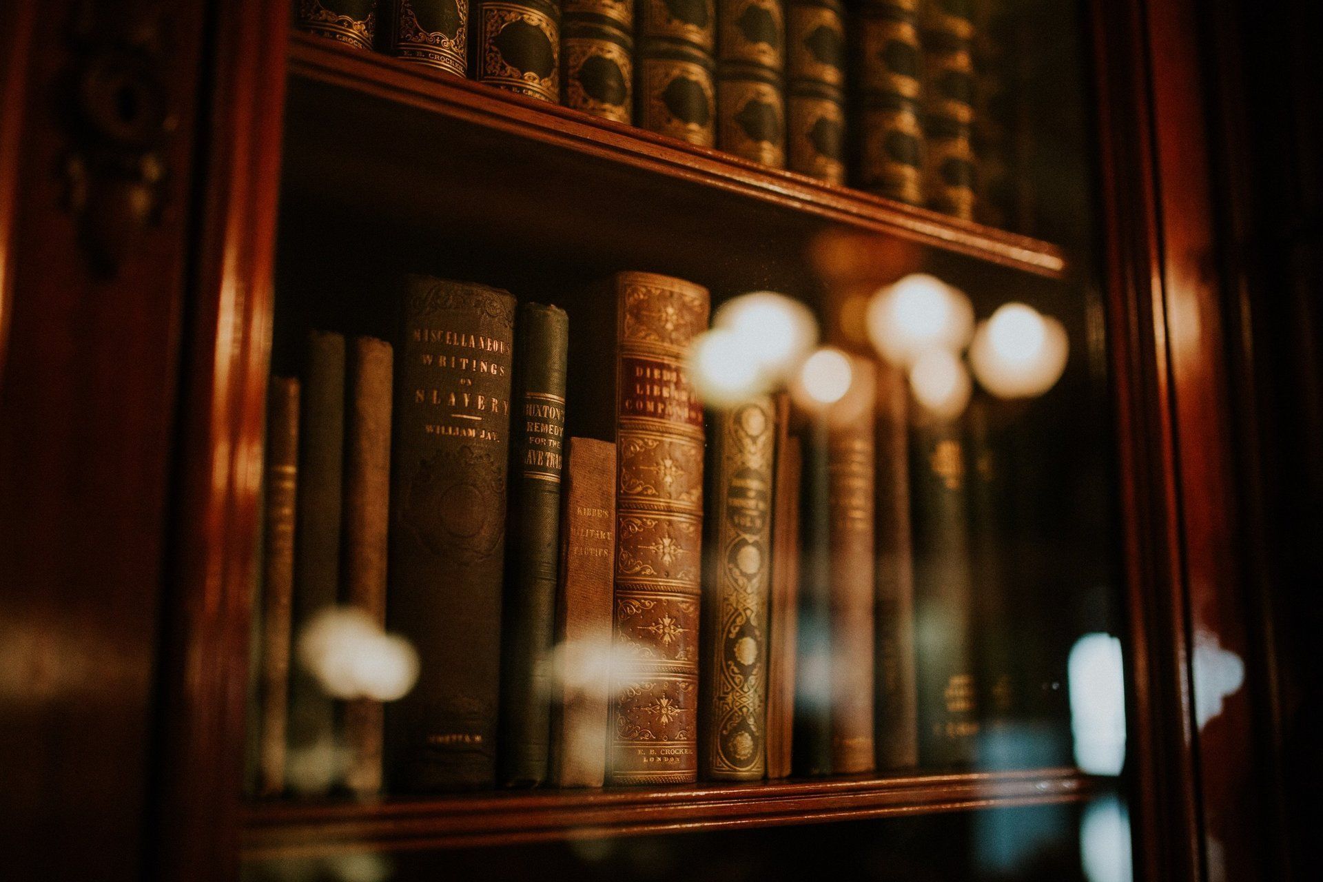 a shelf filled with lots of old books in a library .