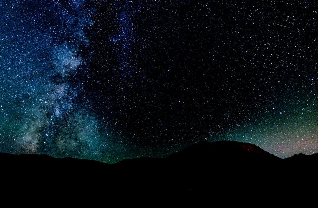 A night sky filled with lots of stars and mountains in the foreground.