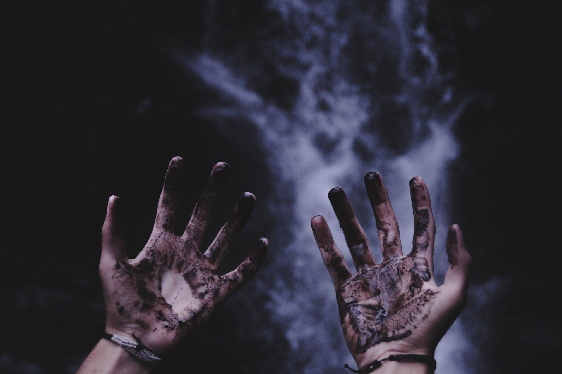 soiled blackened outstretched hands with a body image in the background
