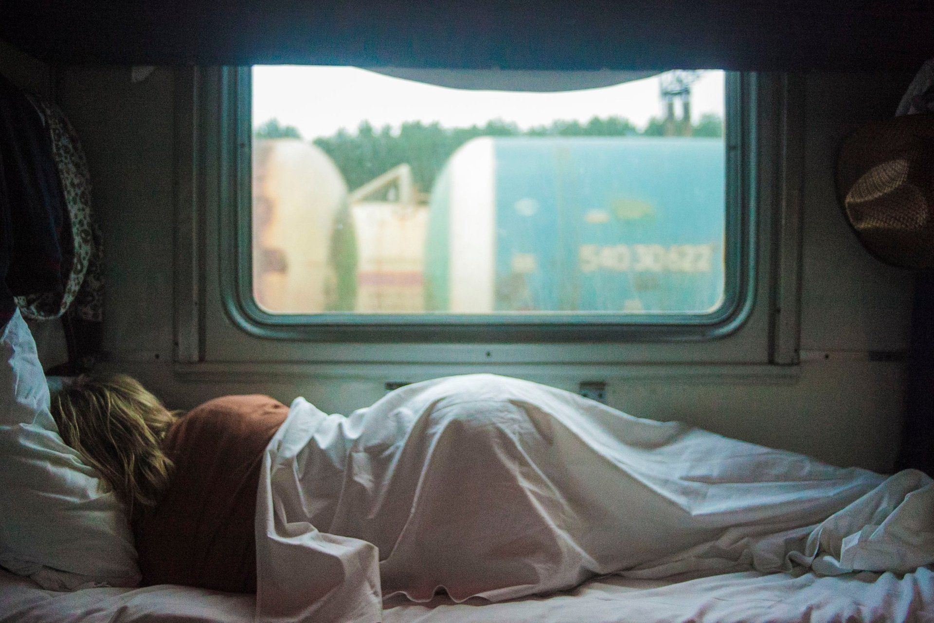 A woman is sleeping on a train next to a window.