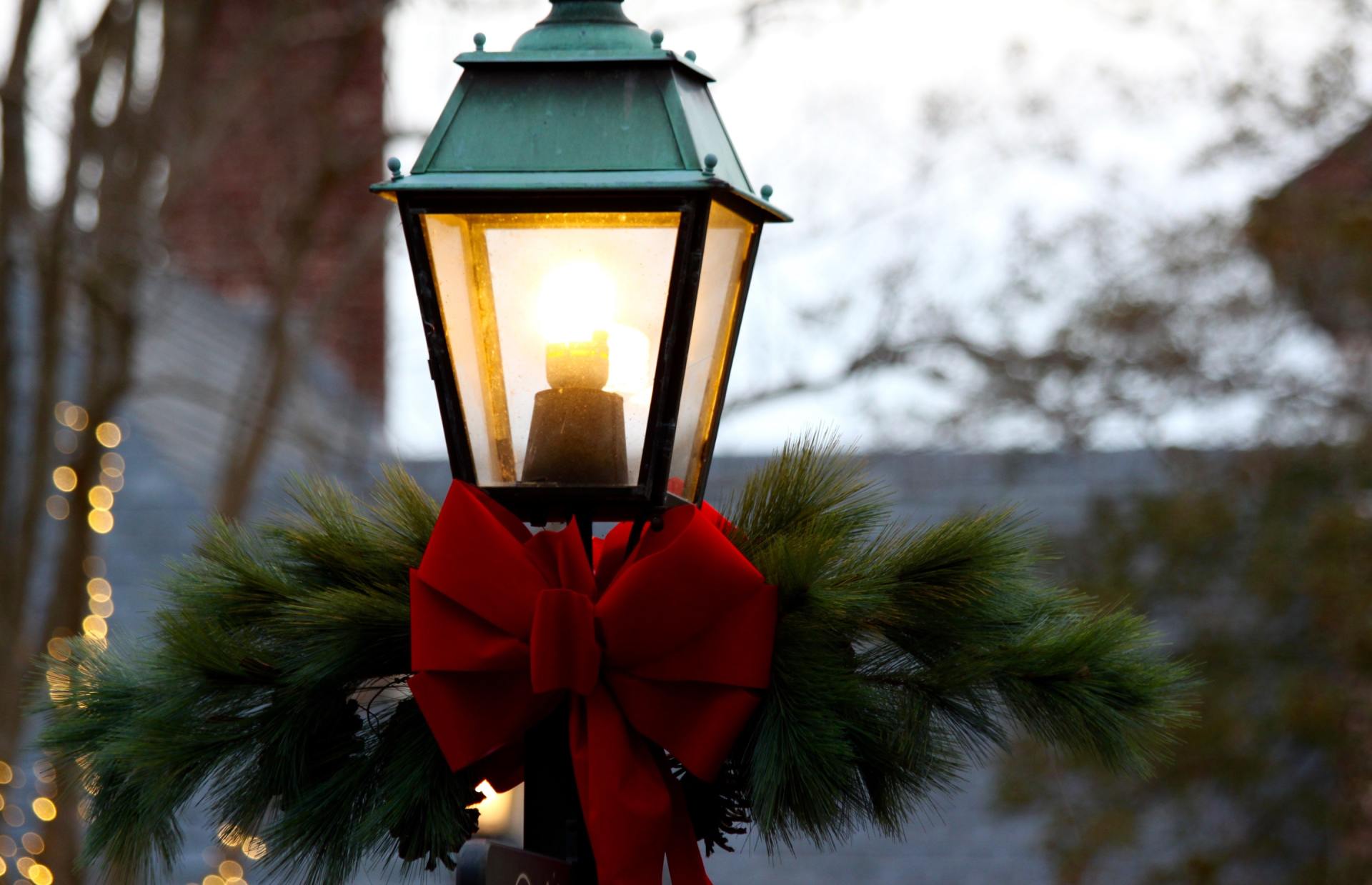 A street light decorated for christmas with a red bow.