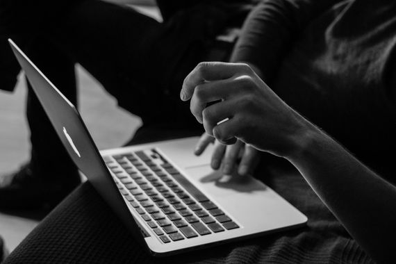 A black and white photo of a person using a laptop