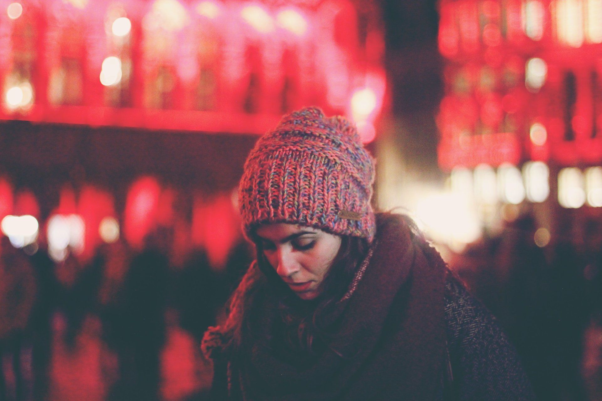 A woman wearing a knitted hat is standing in front of a crowd of people.