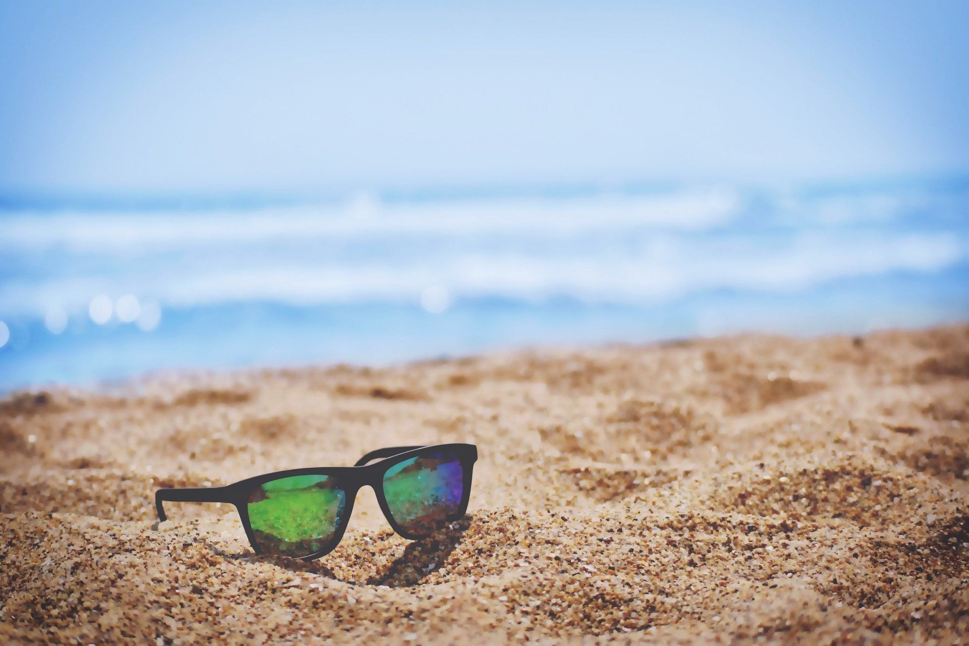 Un paio di occhiali da sole sulla sabbia in una spiaggia.