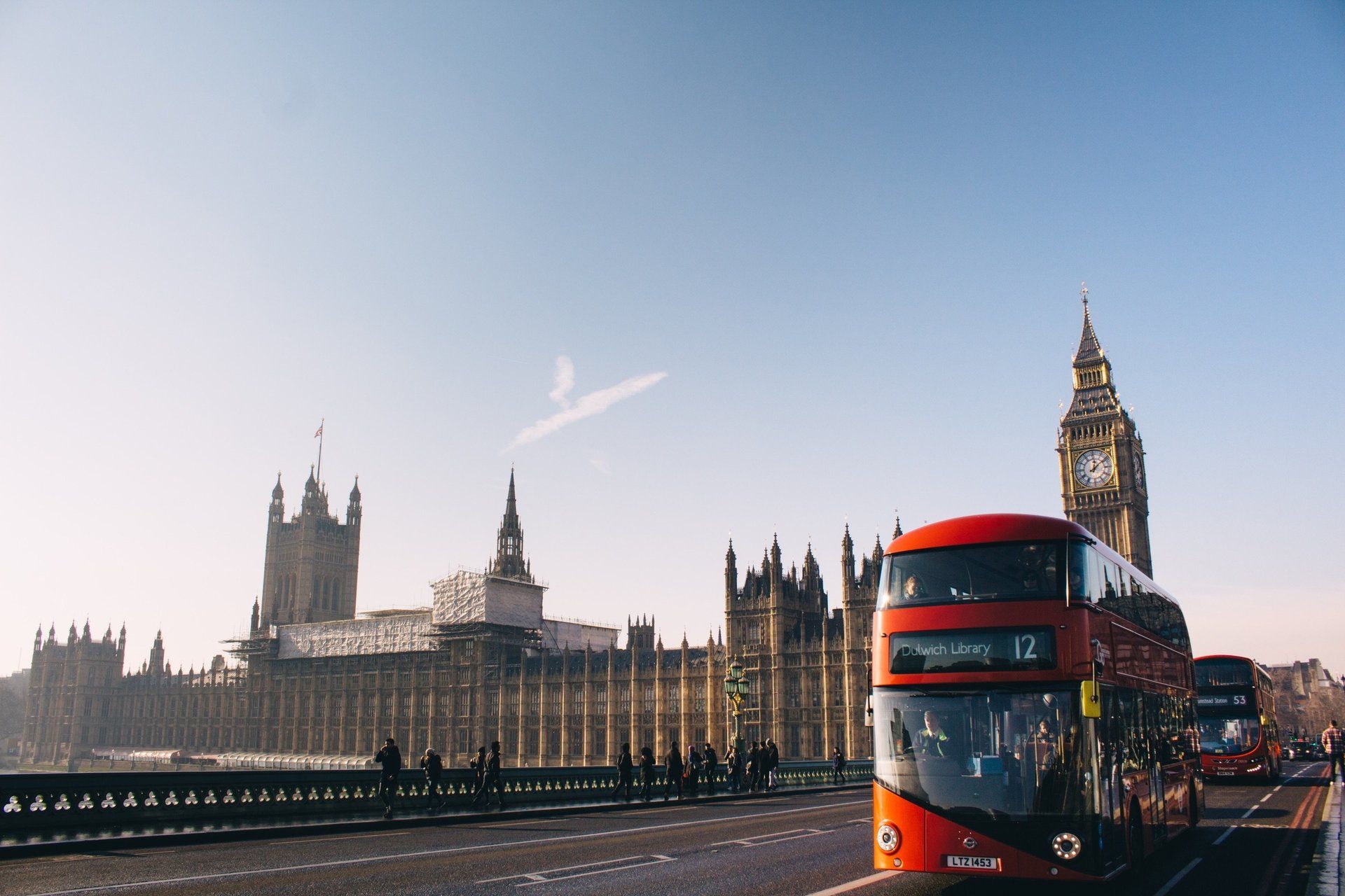 un autobus a due piani su un ponte con la torre dell'orologio di Londra sullo sfondo .