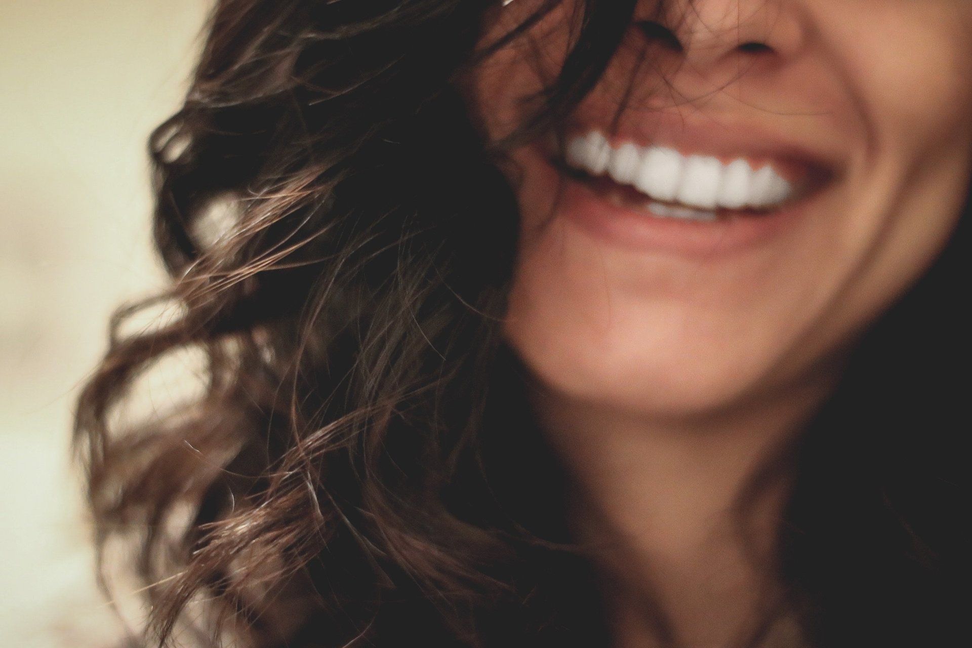 a close up of a woman 's face smiling with her hair blowing in the wind .
