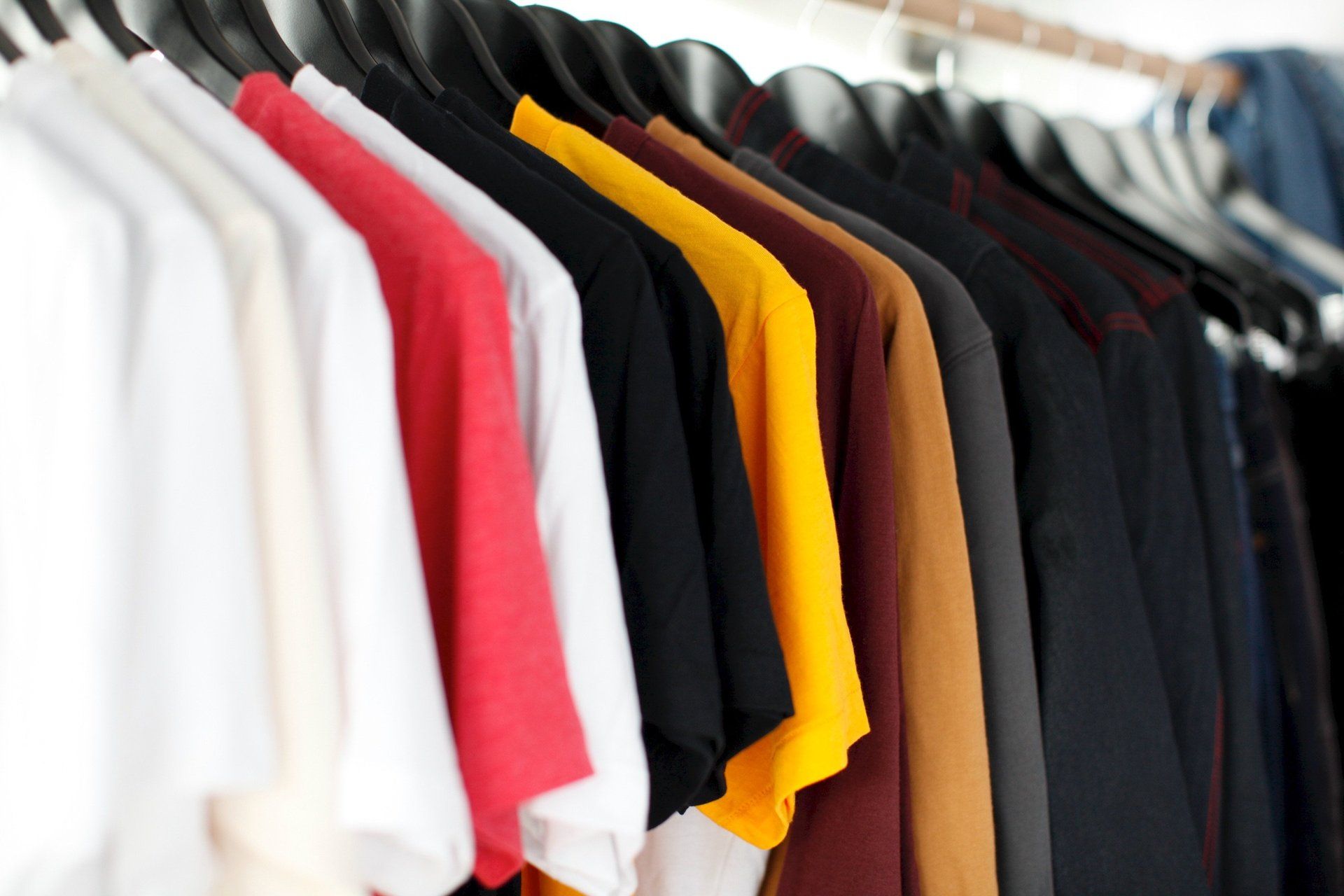 a row of colorful t-shirts are hanging on a rack