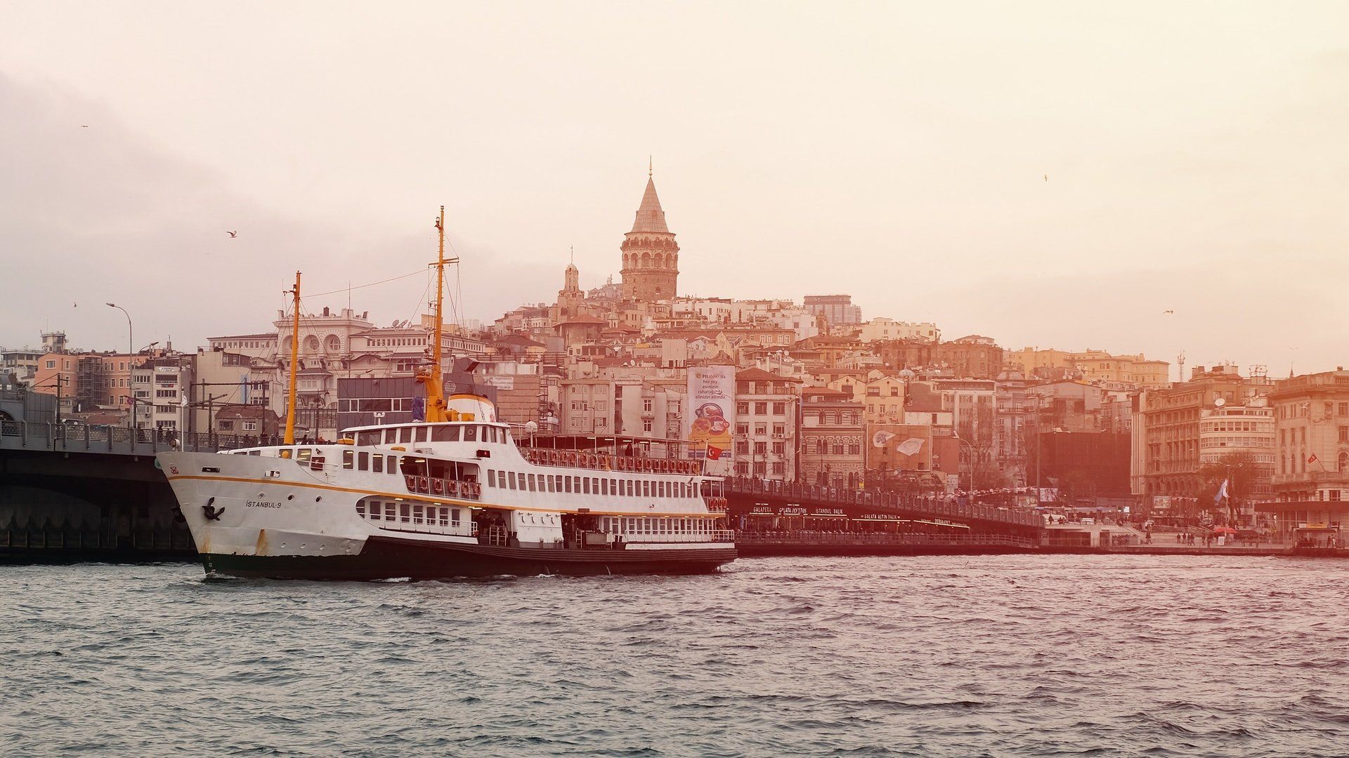 A boat is floating on top of a body of water in front of a city.