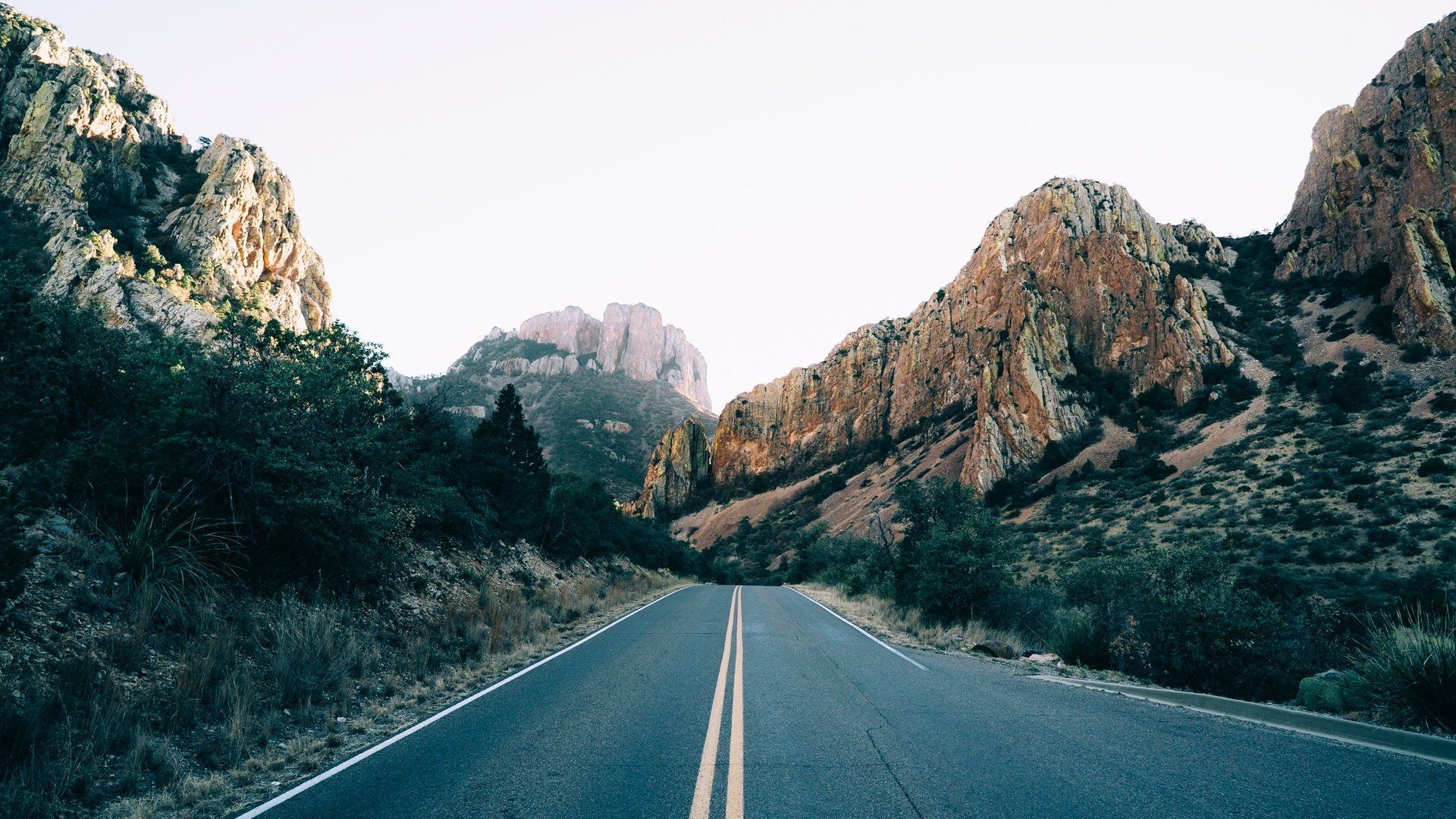 A road going through a valley with mountains in the background
