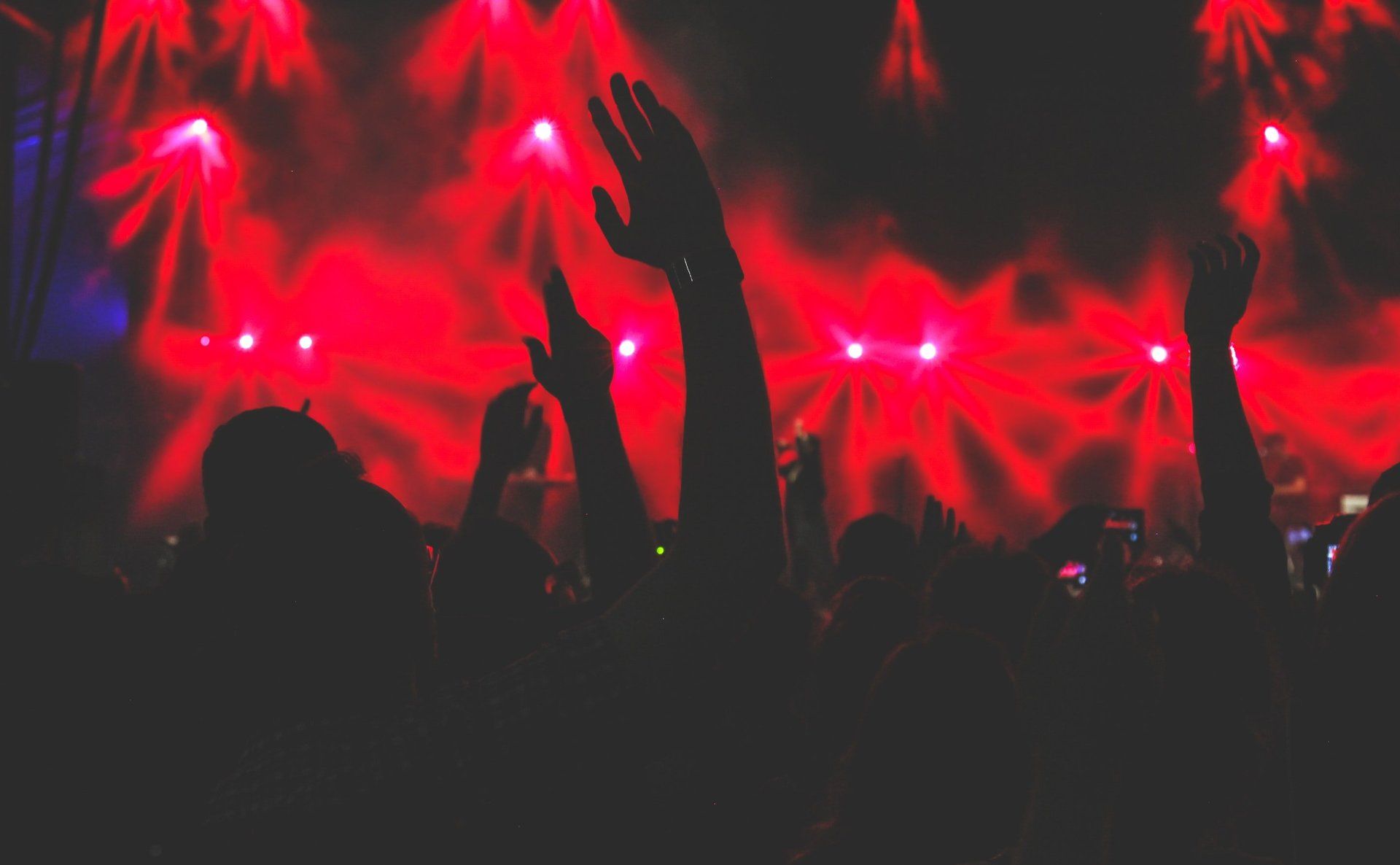 A crowd of people are raising their hands in the air at a concert.