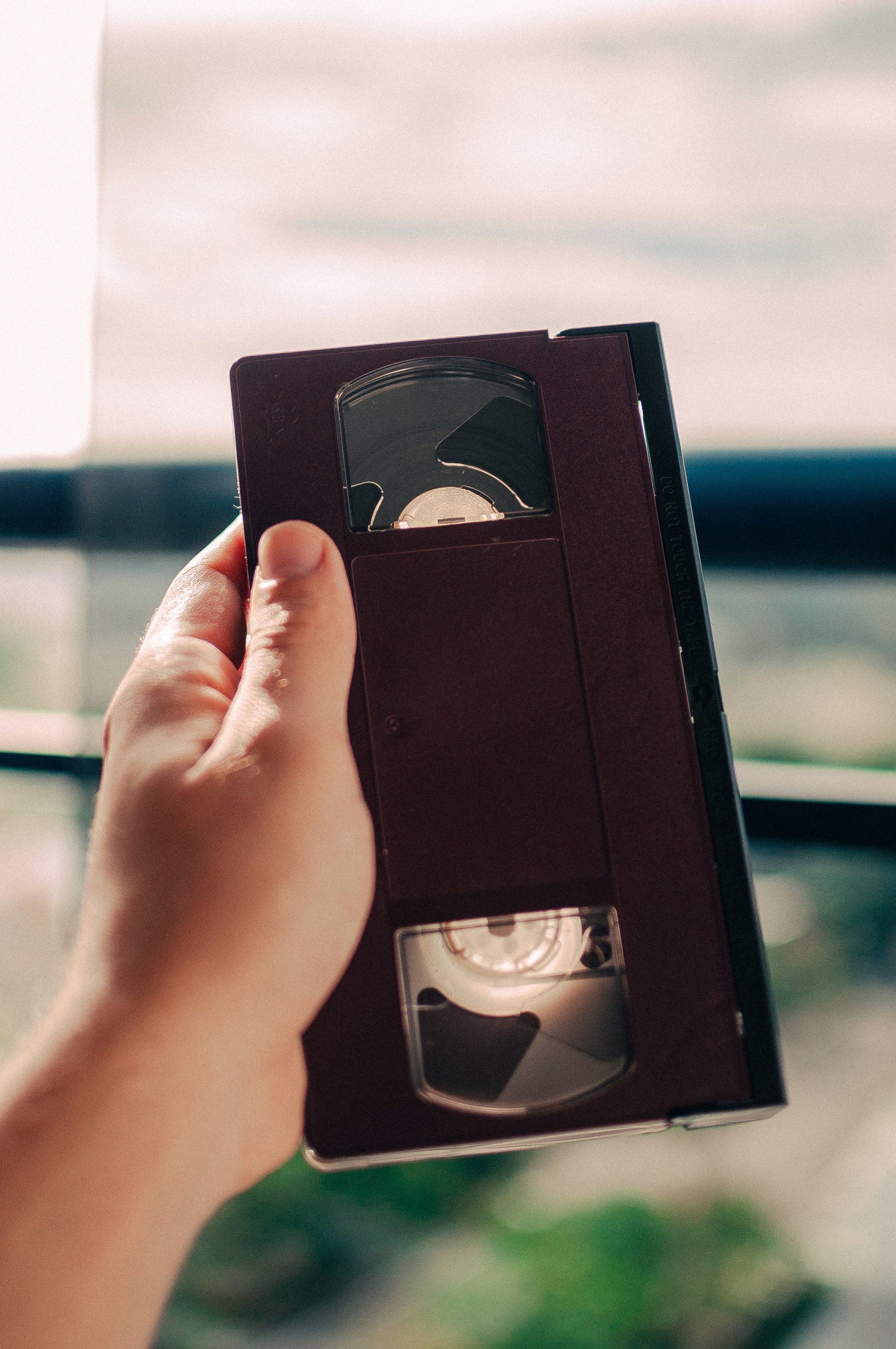 A person is holding a vhs tape in their hand.