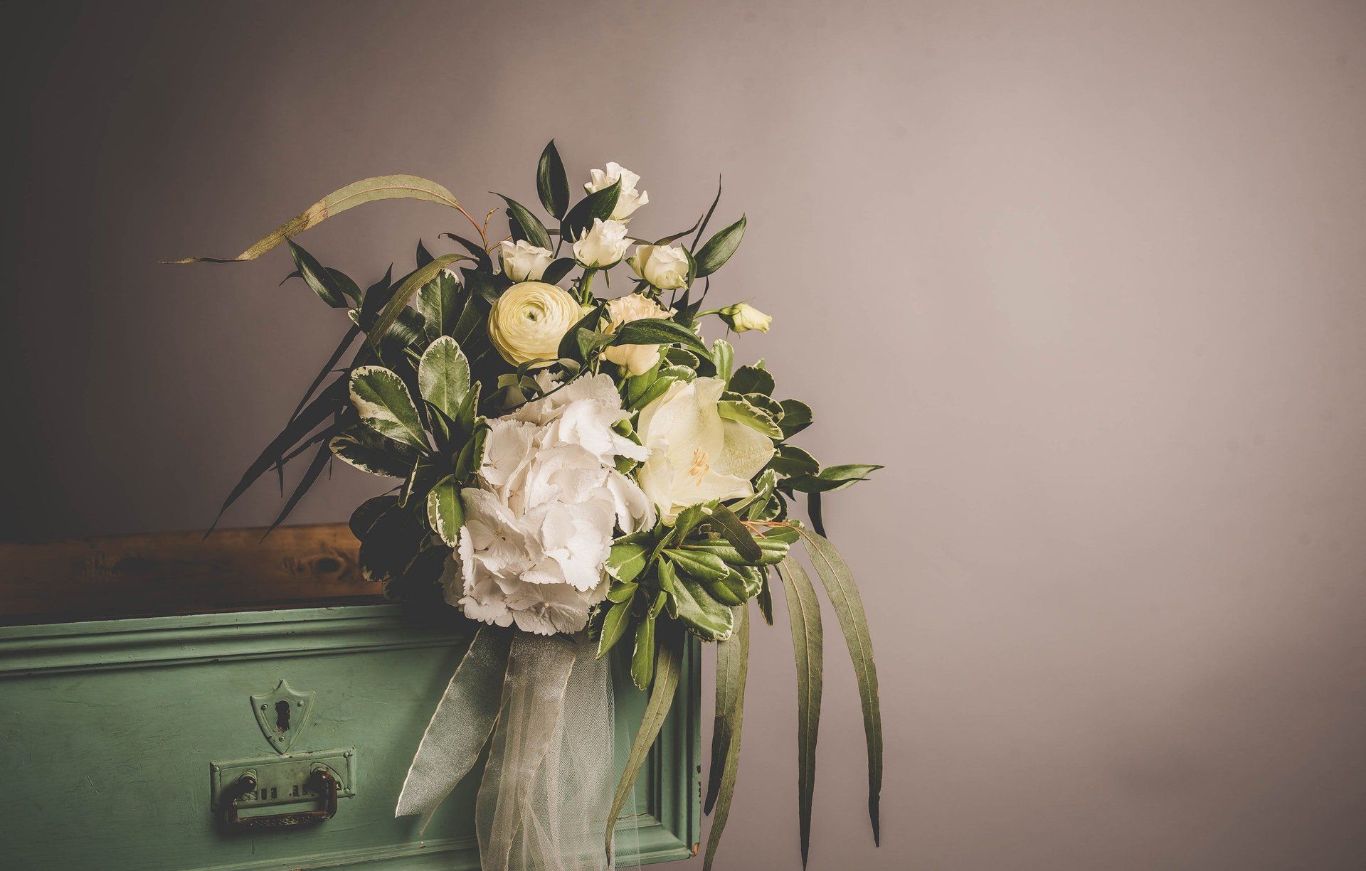 A bouquet of flowers is sitting on a green dresser.
