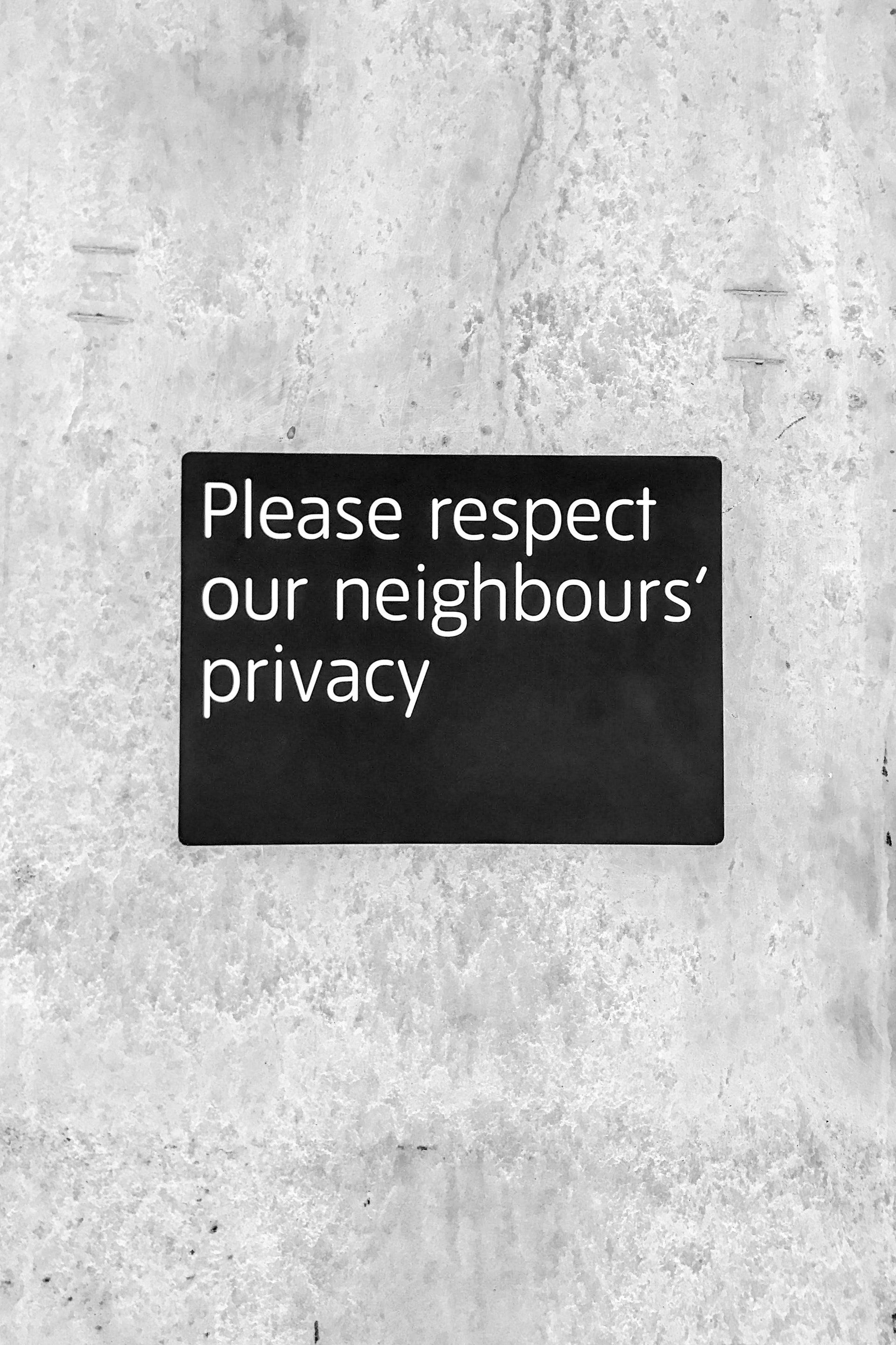 A sign on a wall that says please respect our neighbours privacy