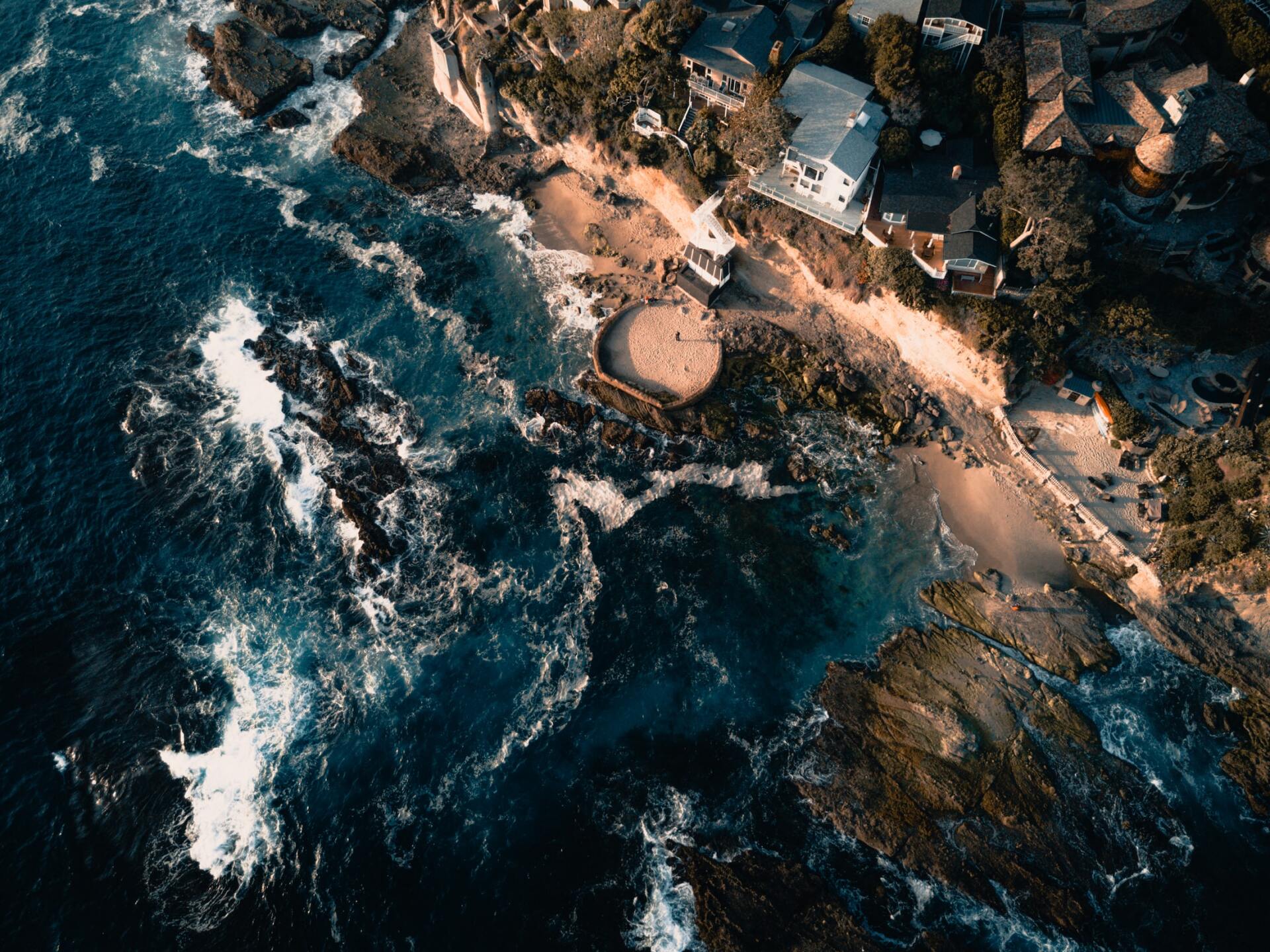 An aerial view of a beach with waves crashing on the rocks.