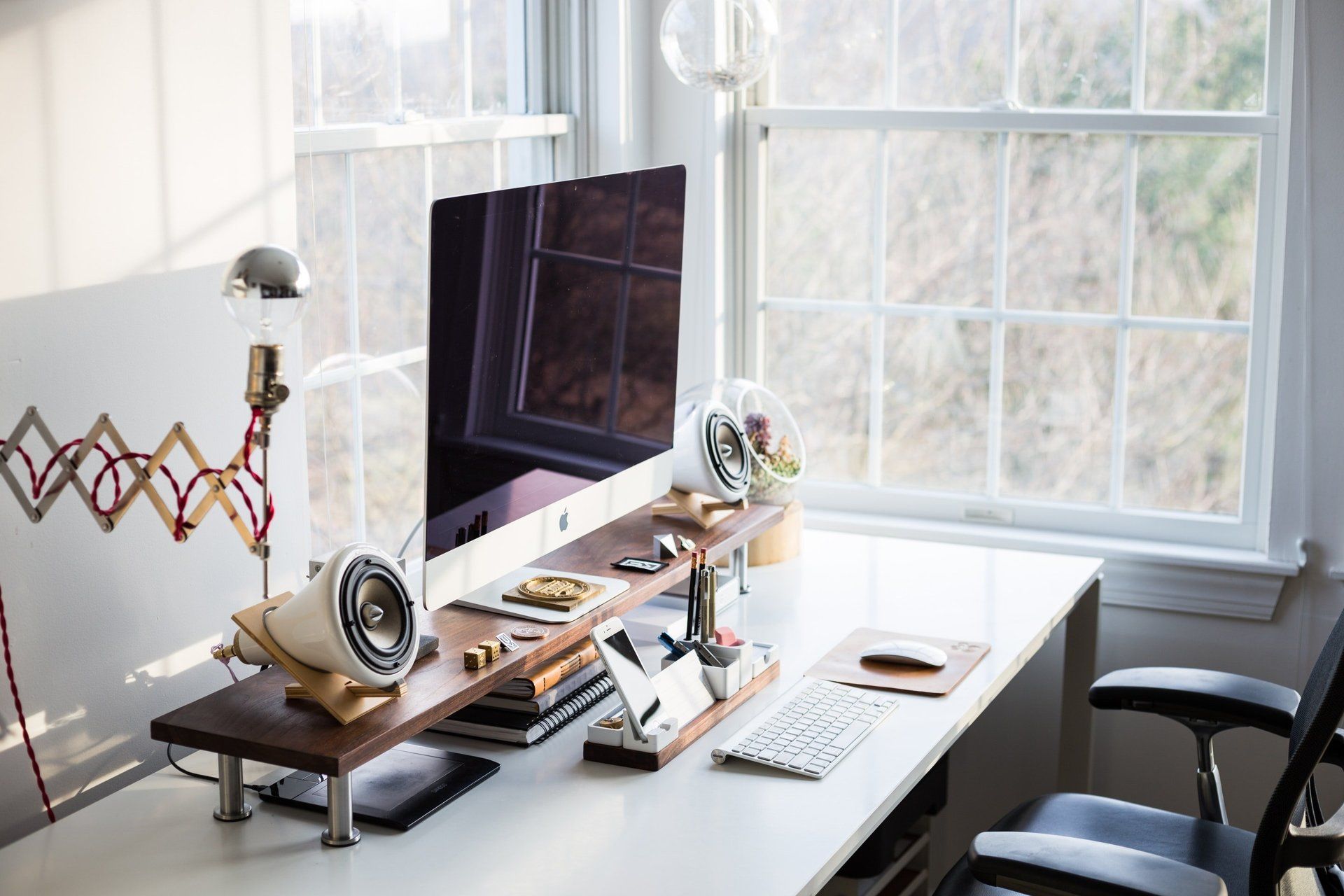 A computer is sitting on top of a desk next to a window.