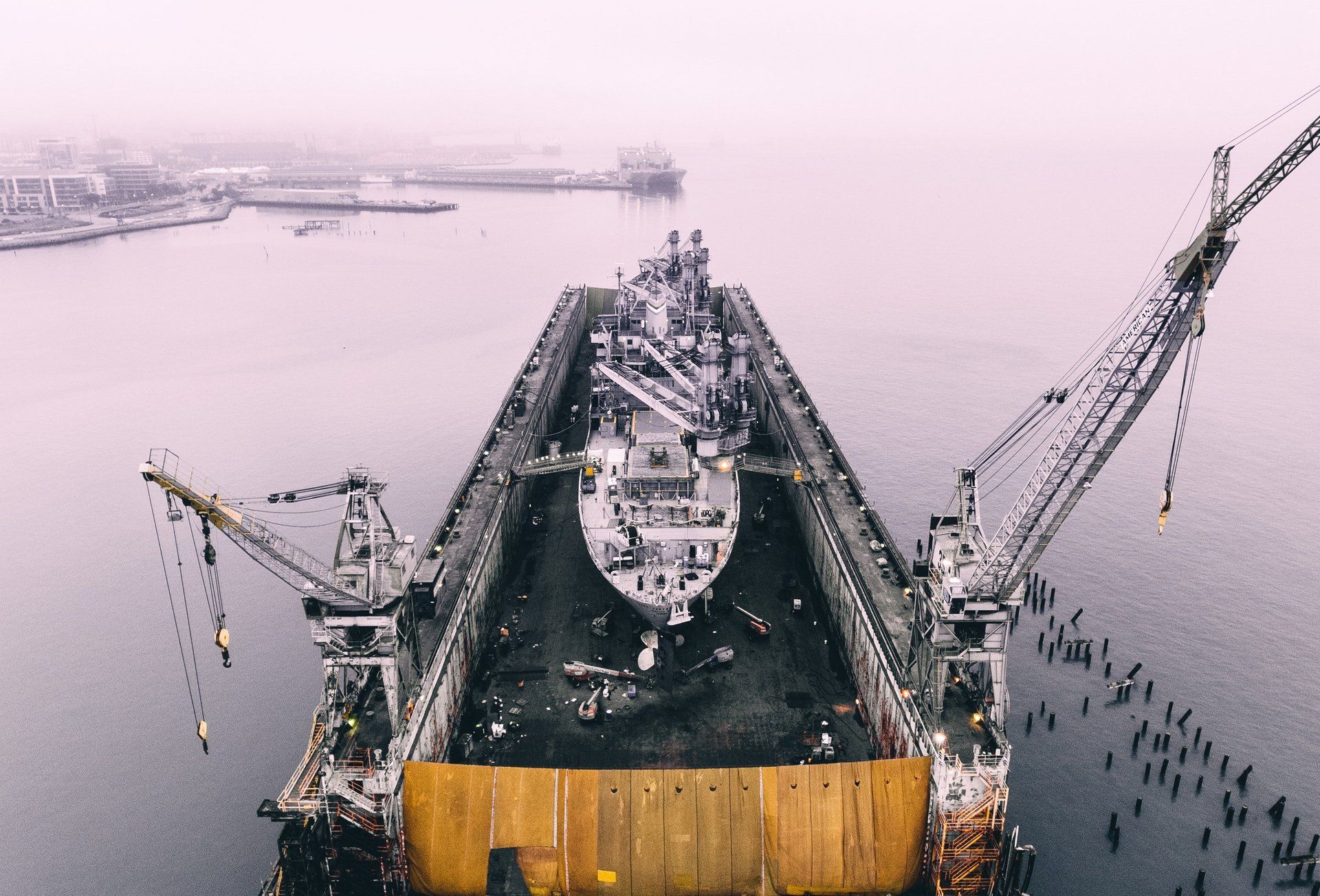 An aerial view of a large ship being built in a shipyard dry dock.