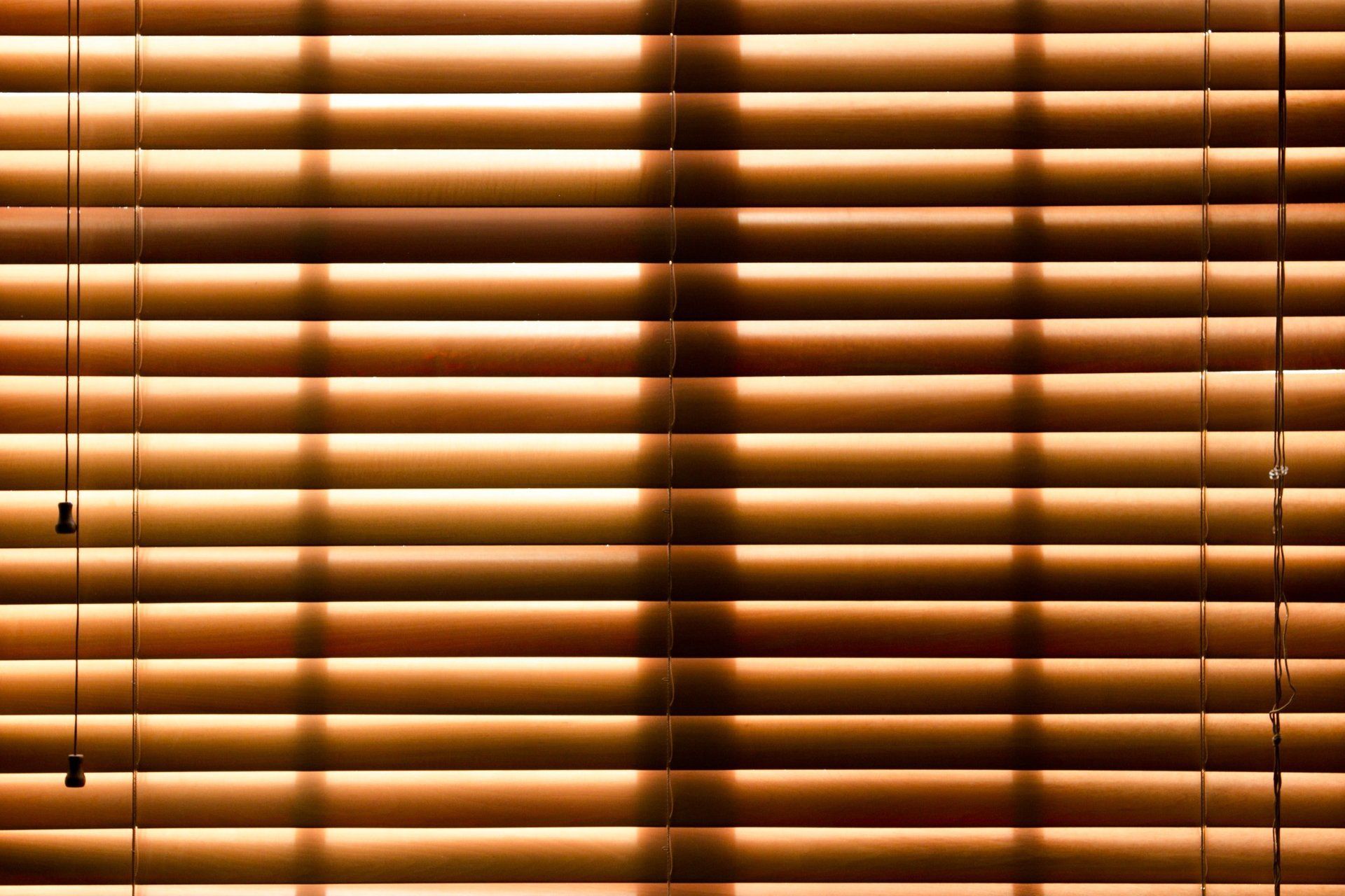 A close up of a pair of wooden blinds on a window.