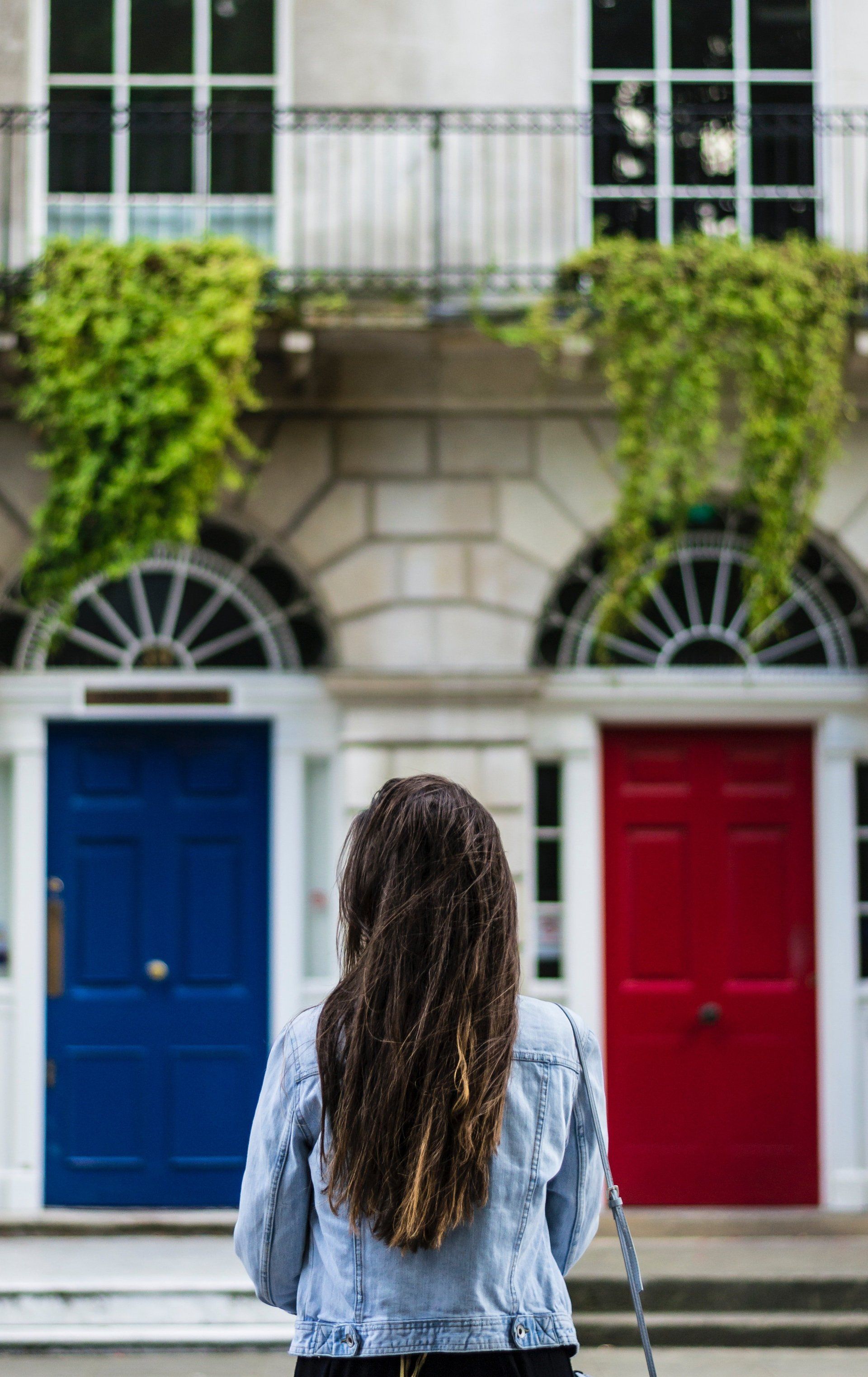 A woman is standing in front of a blue and red door.