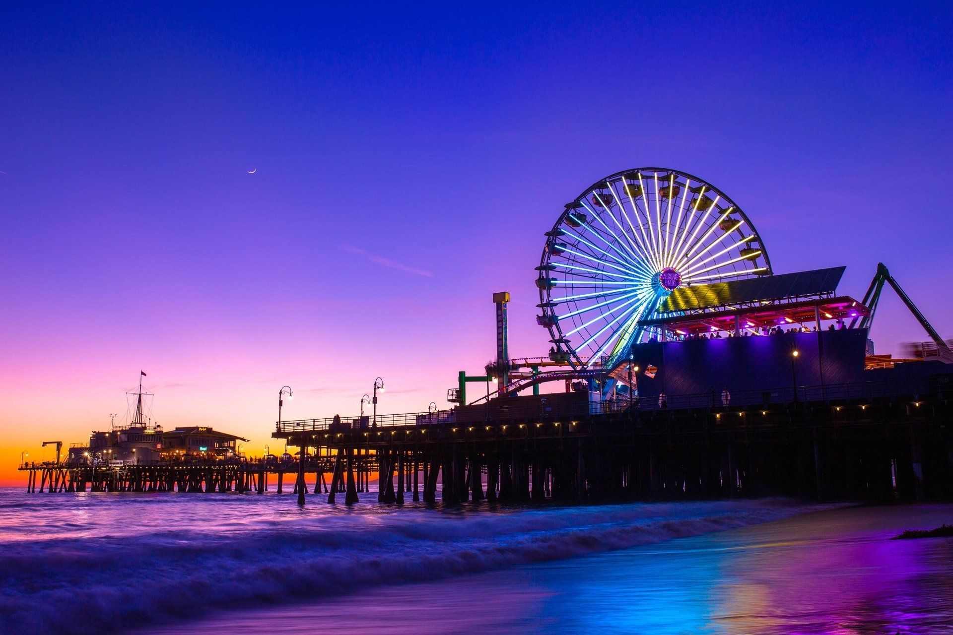 There is a ferris wheel on the pier at night.