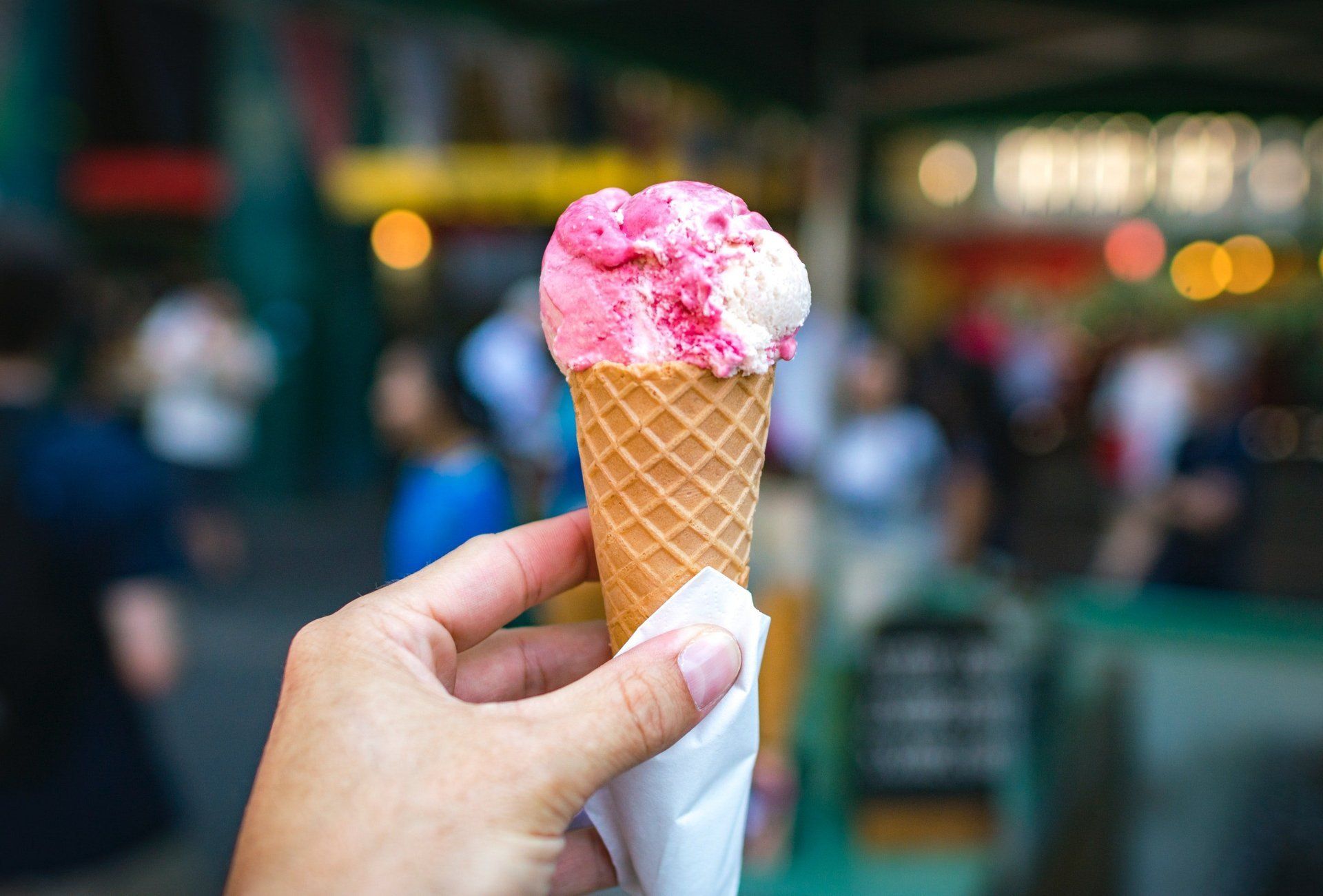 A person is holding a pink and white ice cream cone.