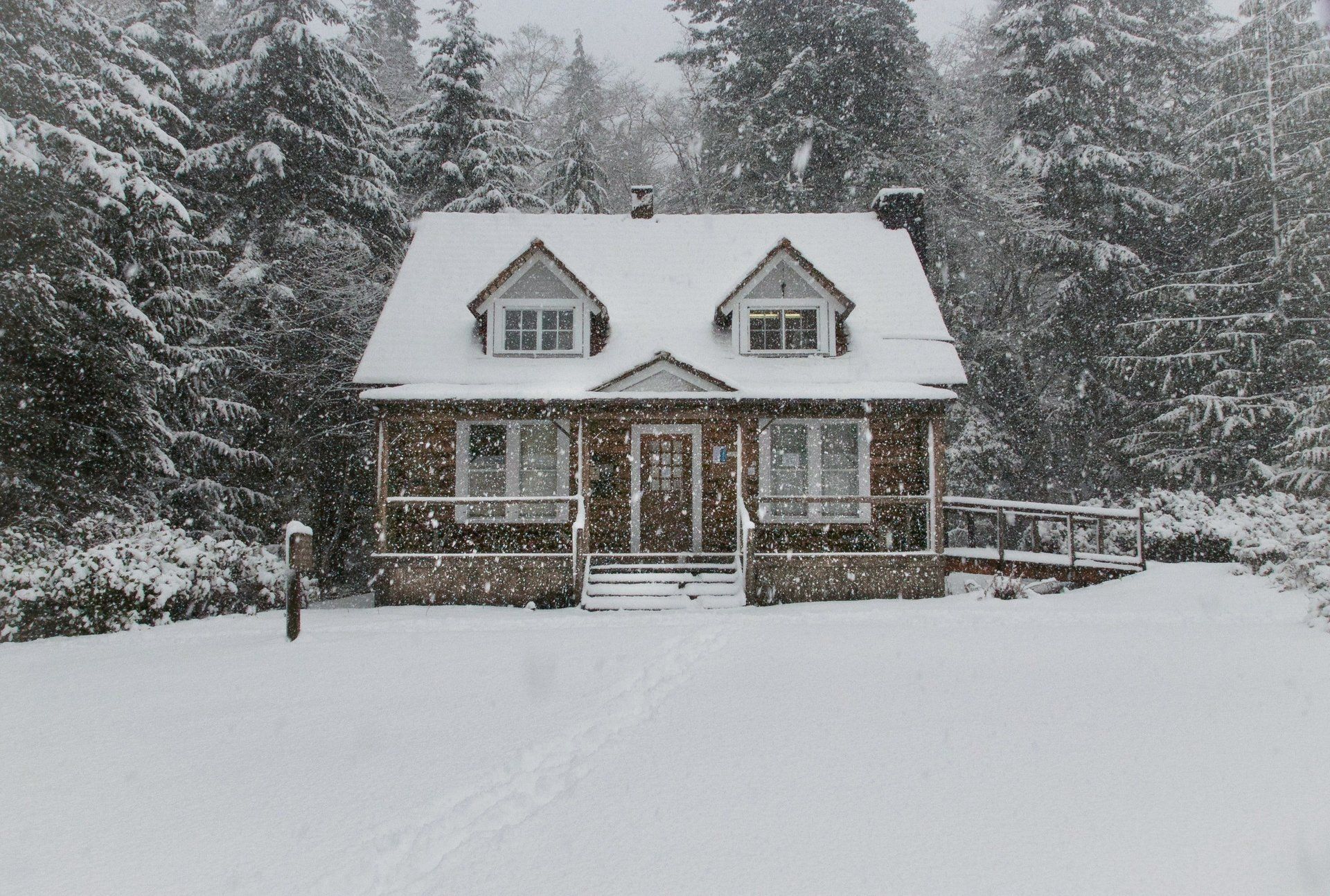 A log home surrounded by snow during a winter storm