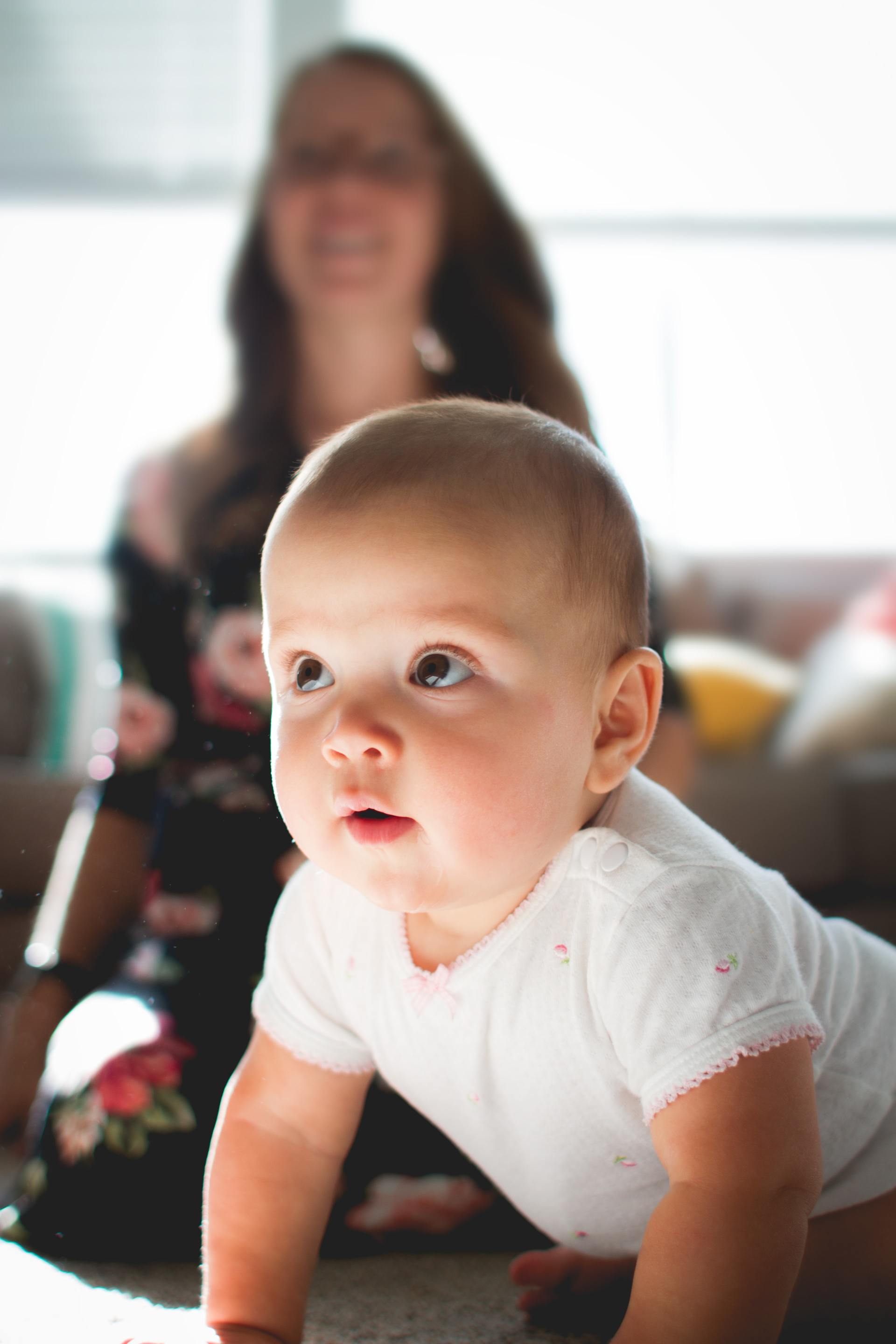 baby on hands with mother by side