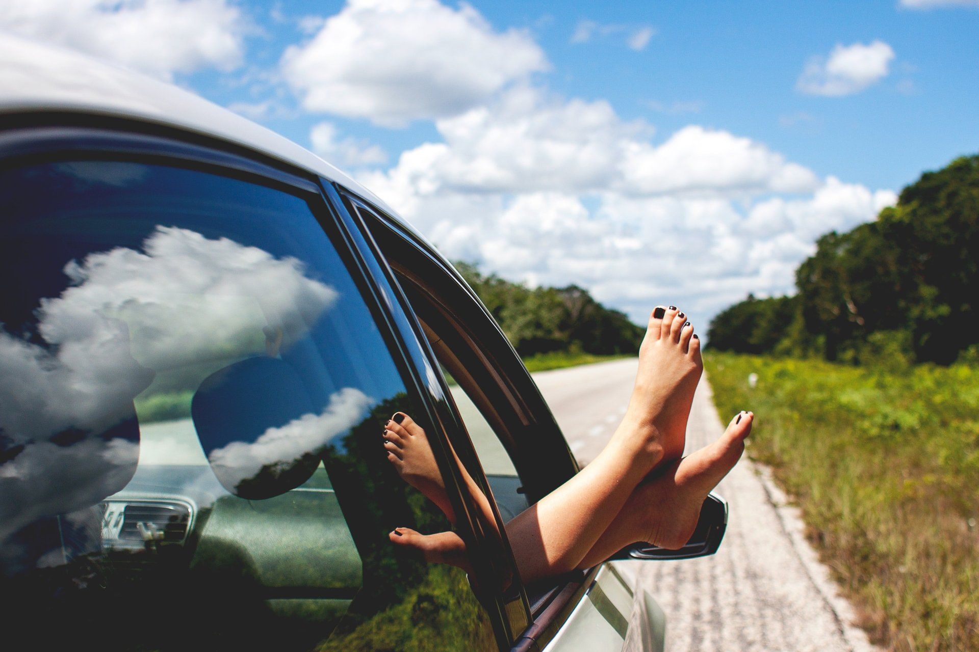A person props their feet out of an opened car window by a highway. A woman props her feet out of an opened car window in West Chester, OH.
