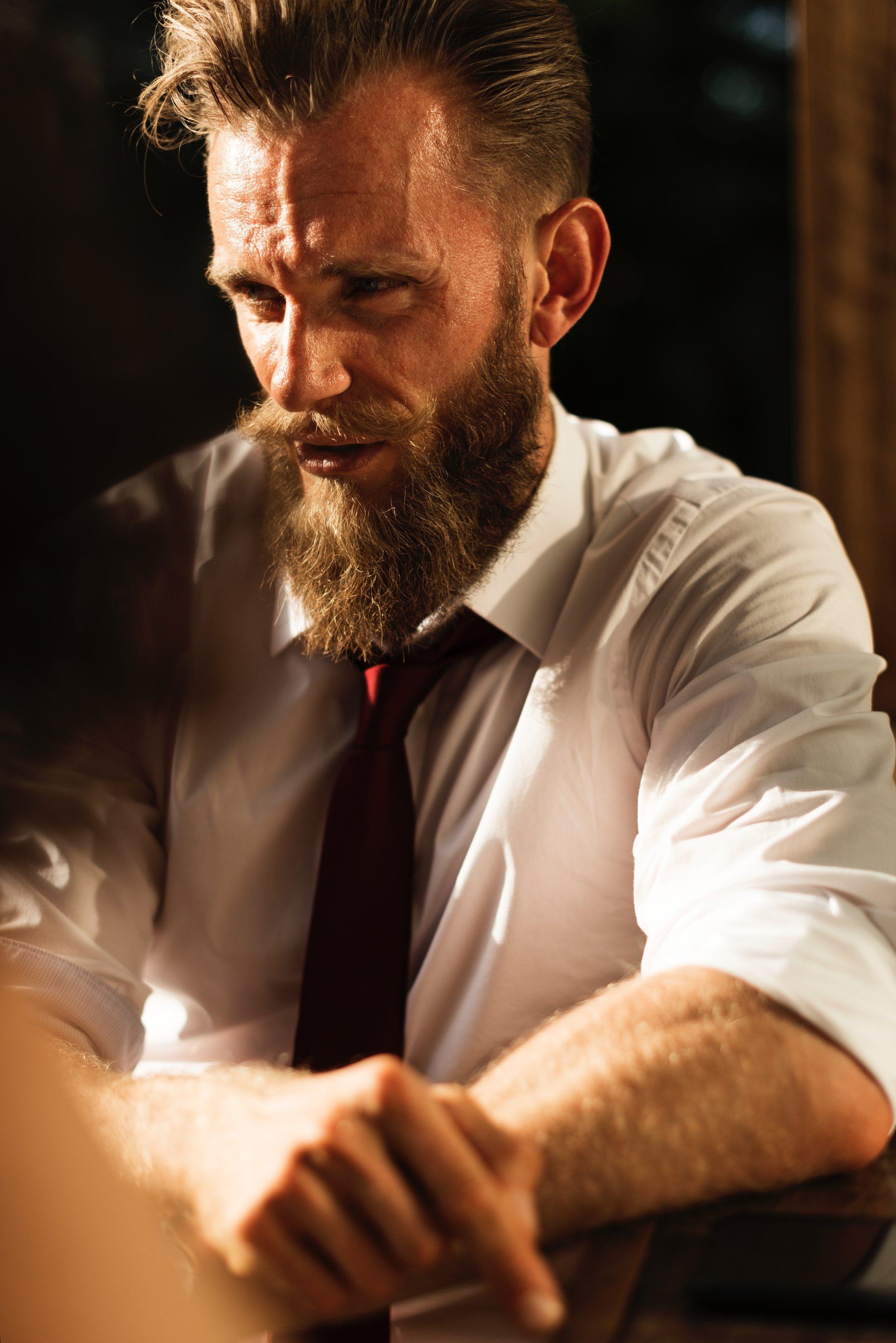 A man with a beard and tie is sitting at a table.