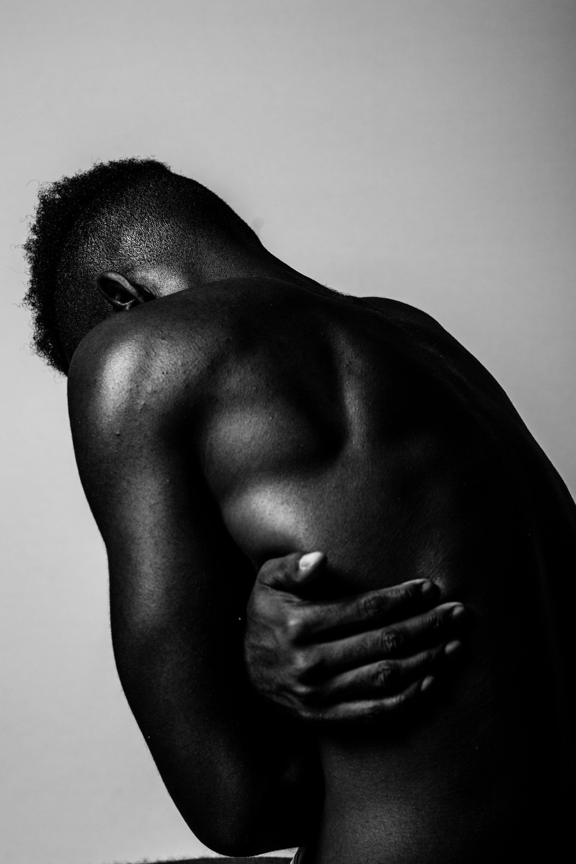 back section and head of a dark skinned person with arms and hands clenching themself