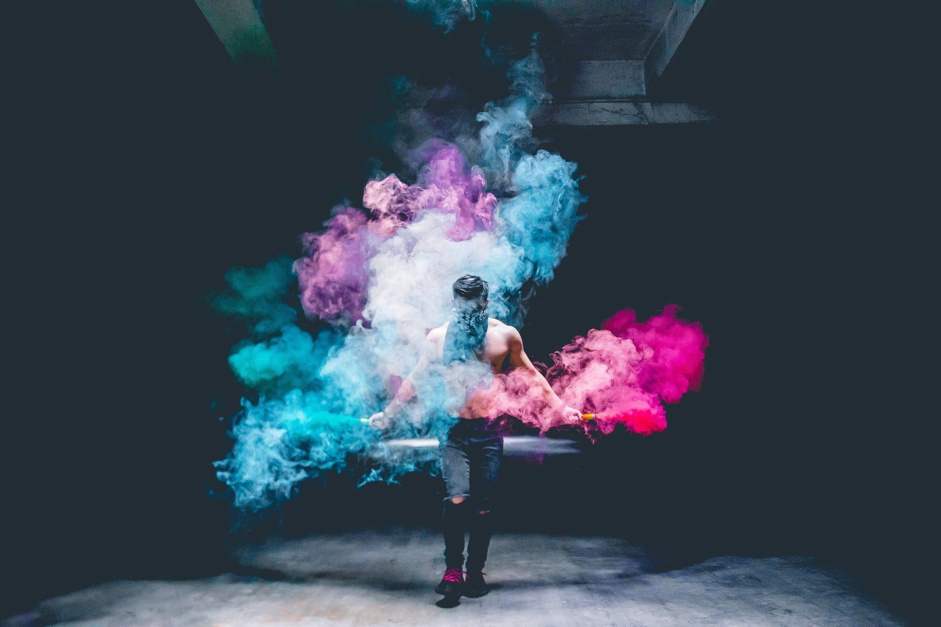 A person is standing in front of a cloud of colorful smoke.
