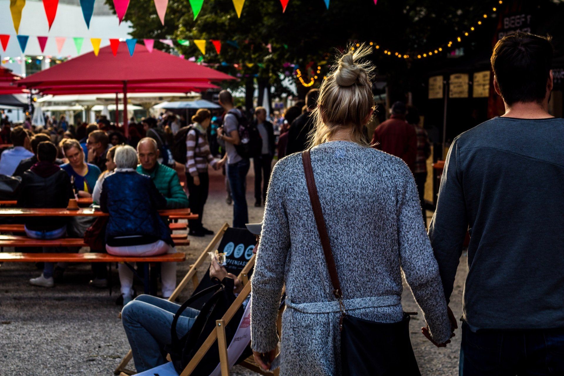 A man and a woman are walking down a street holding hands.