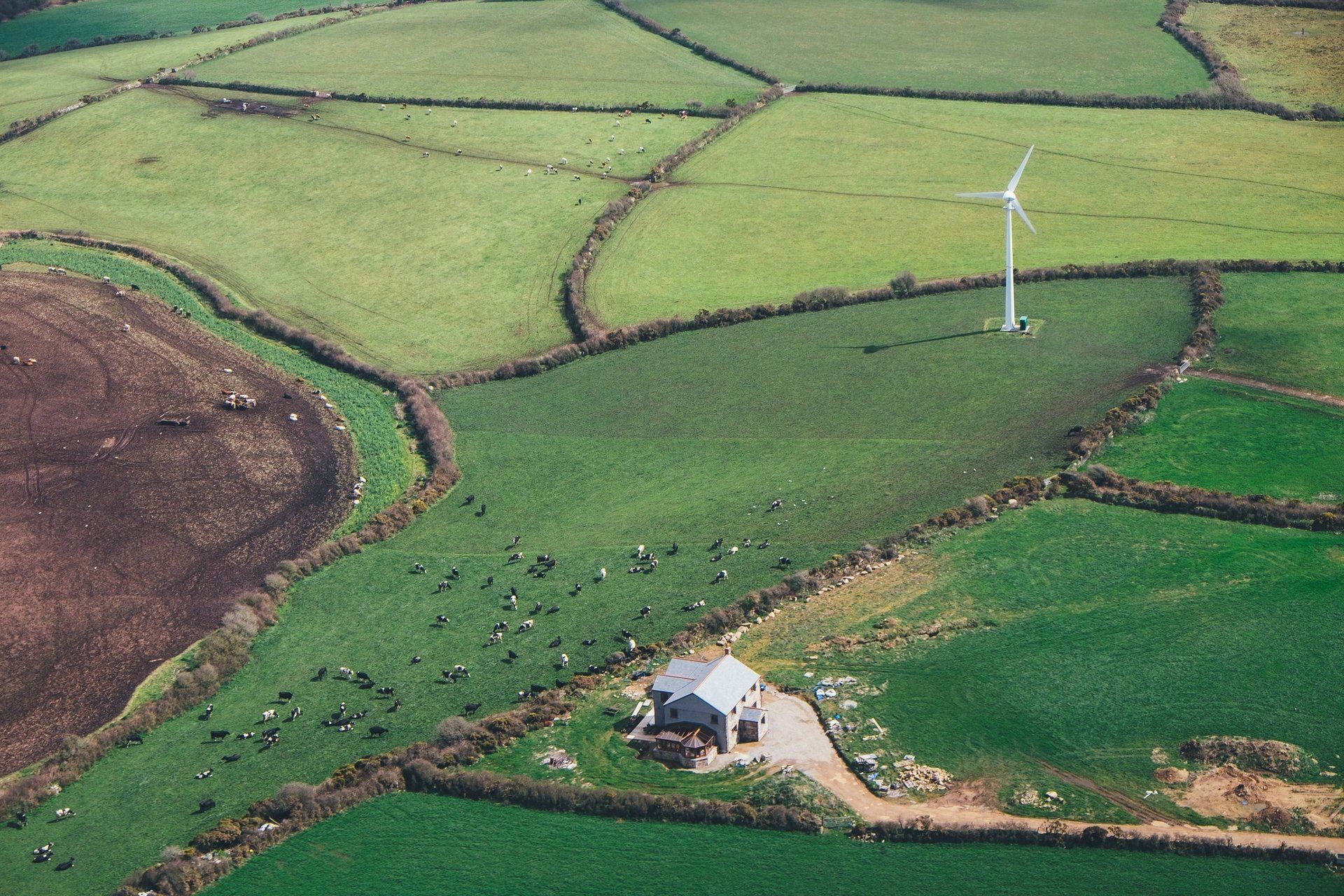 Uma vista aérea de uma fazenda com uma turbina eólica no meio do campo.