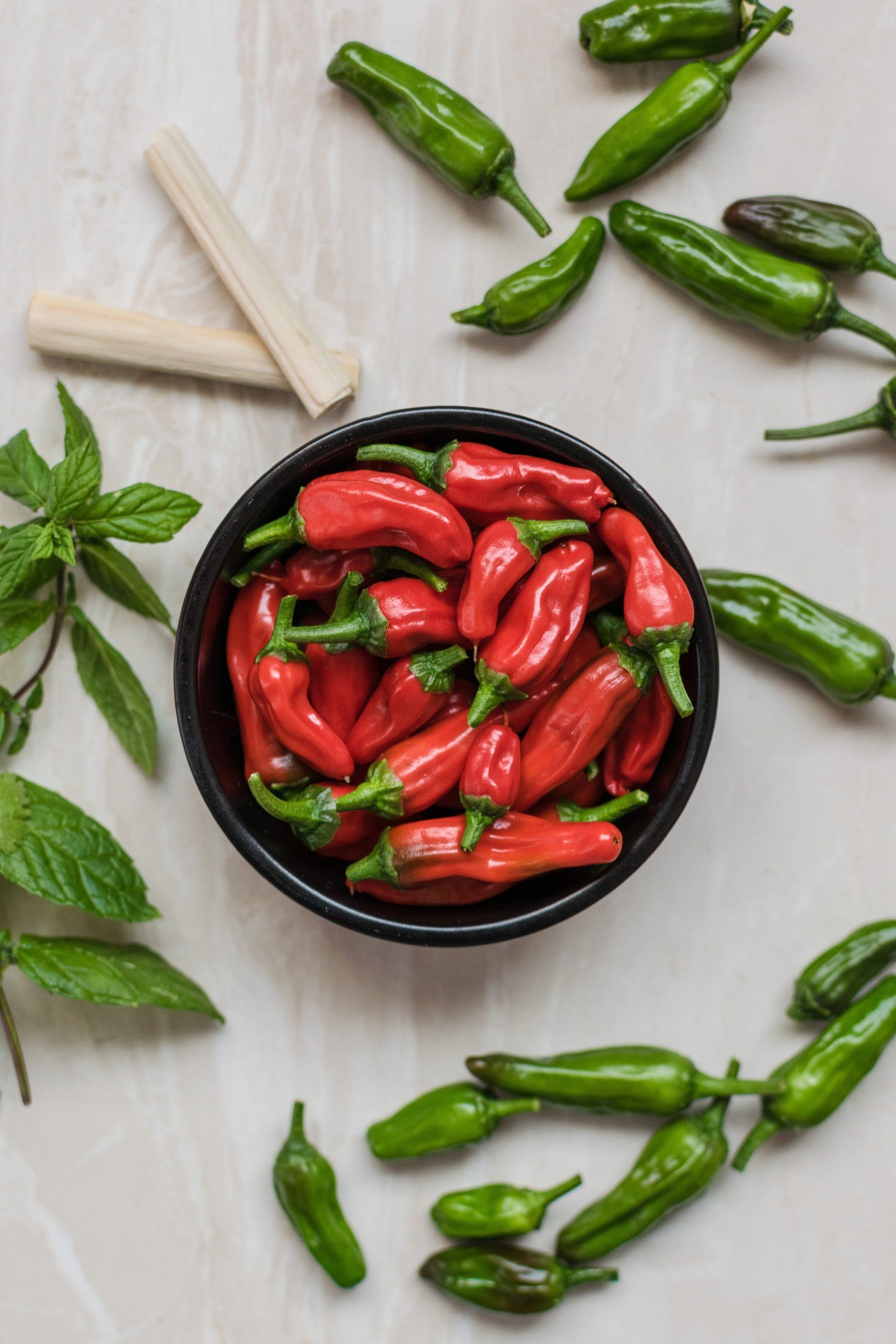 A bowl of red peppers and green peppers on a table.