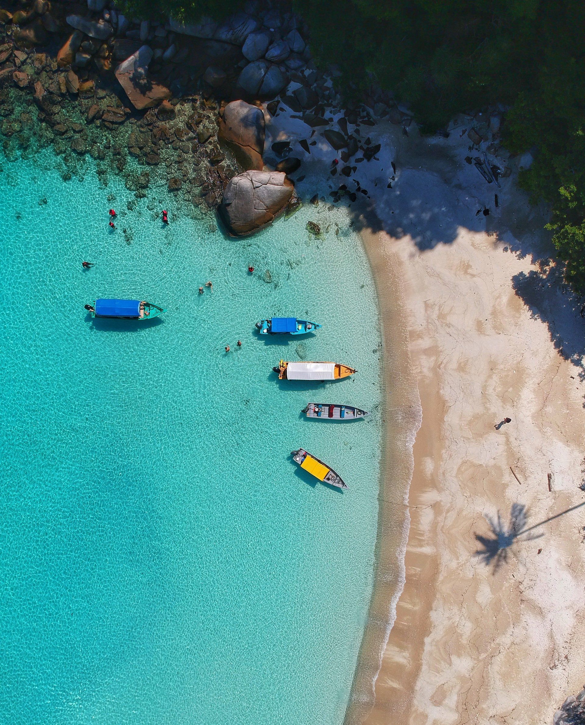 An aerial view of a beach with boats in the water.