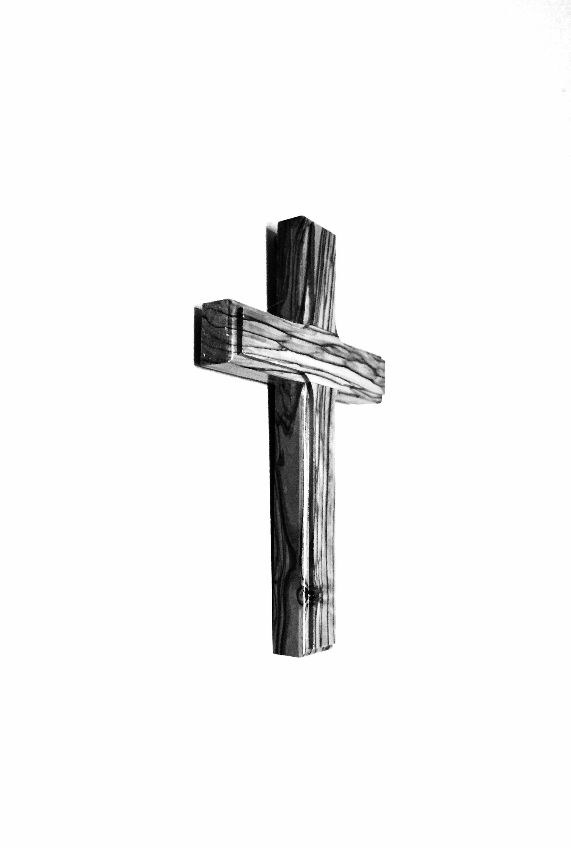 A black and white photo of a wooden cross on a white background.
