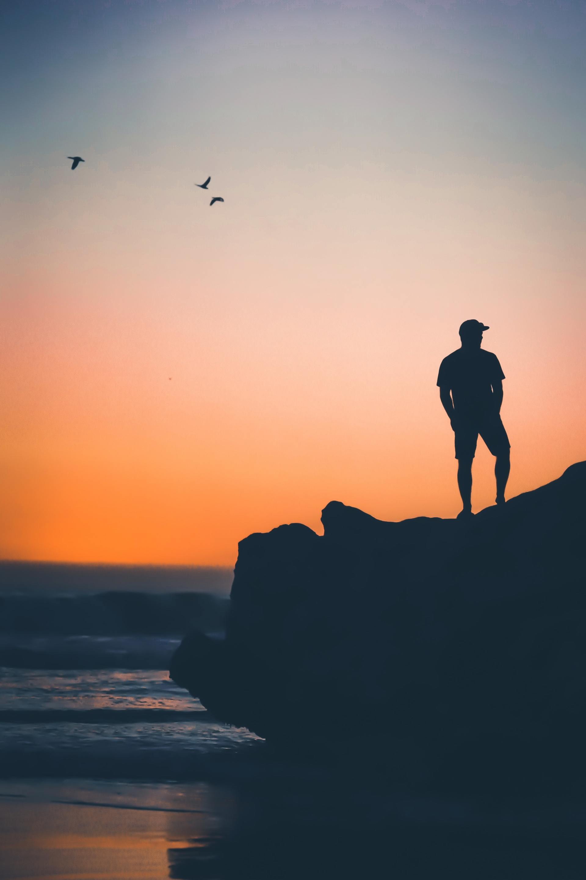 Single man on a mountain with sunset and beach