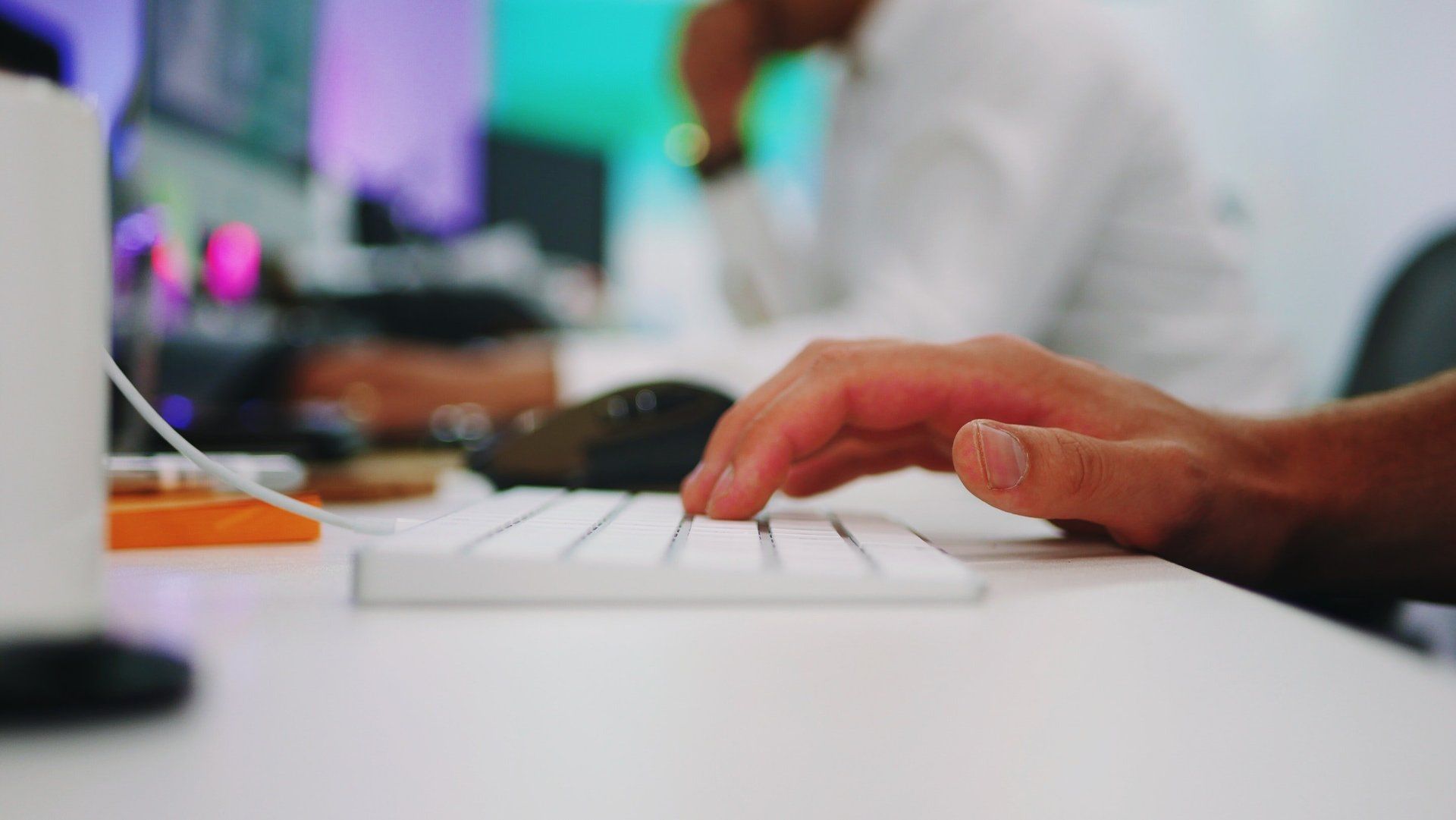 A person is typing on a white keyboard.