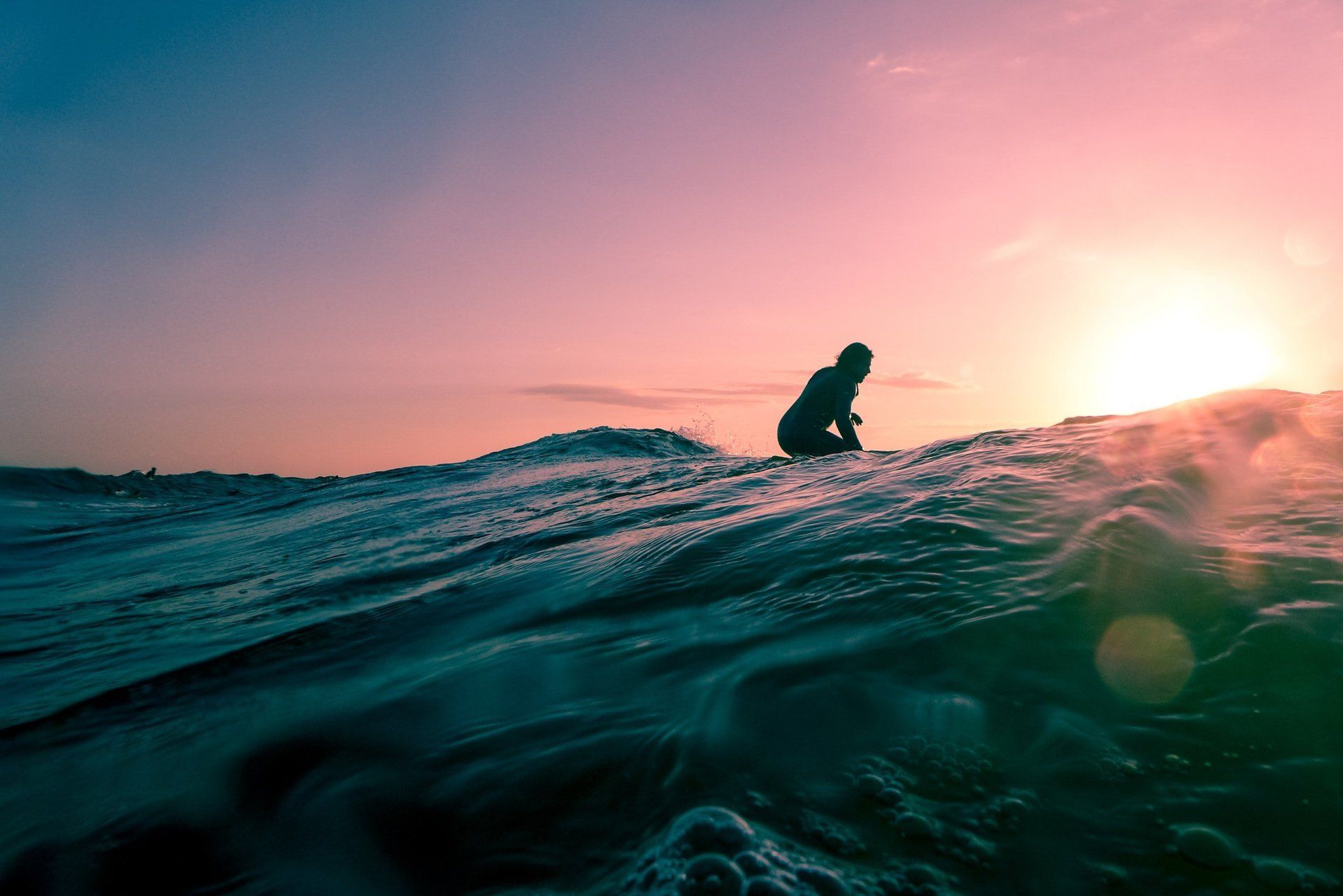 a person is riding a wave in the ocean at sunset