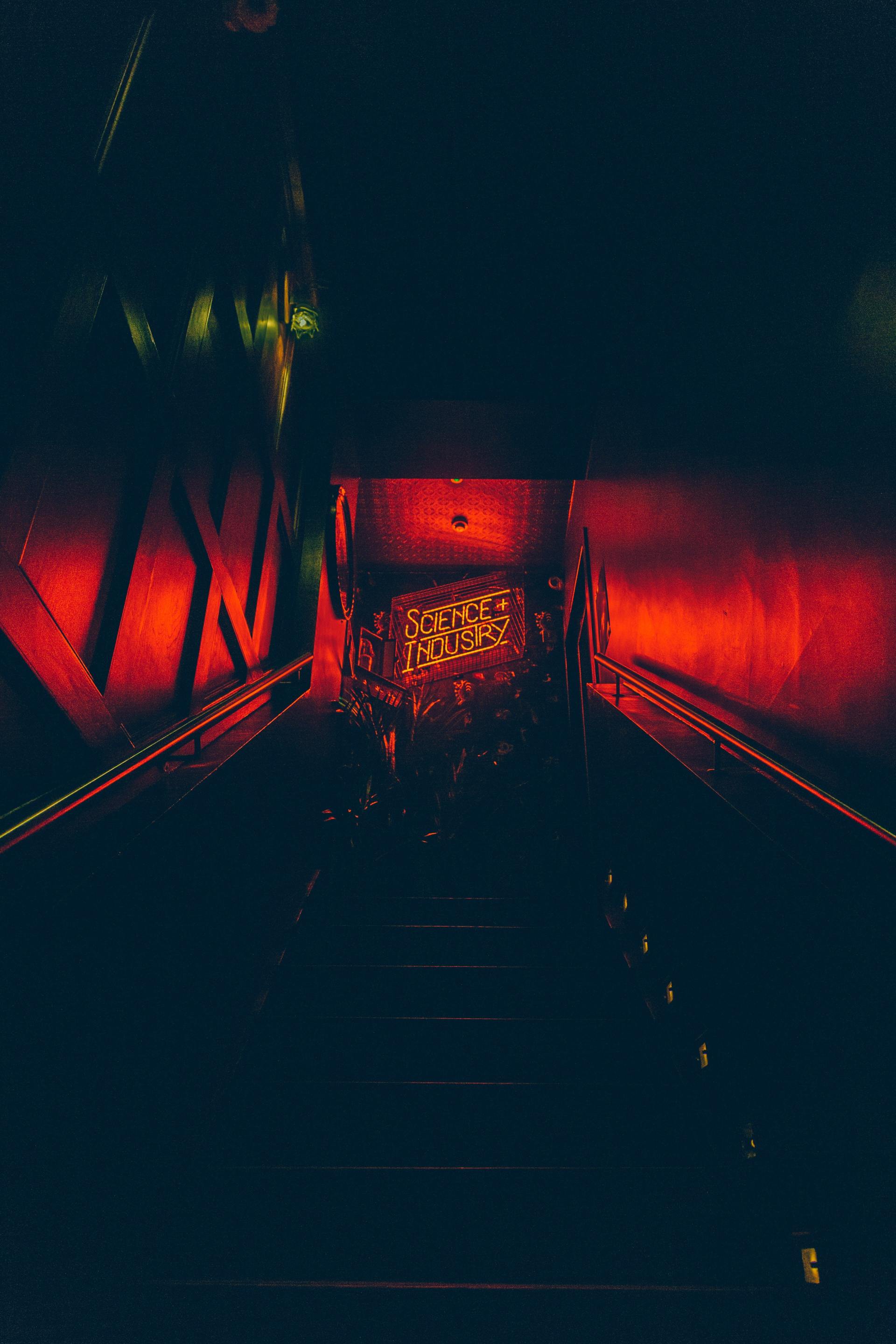 A dark room with red lights on the walls and stairs